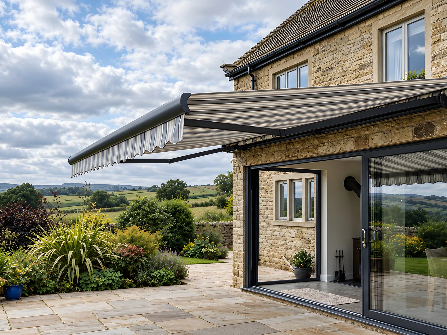 Striped retractable awning extended over a stone house patio