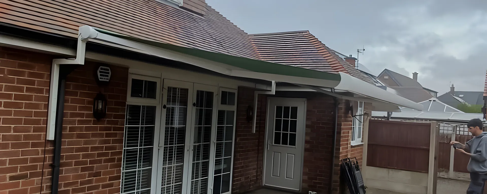 Green retractable awning extended over patio doors at the back of a brick house