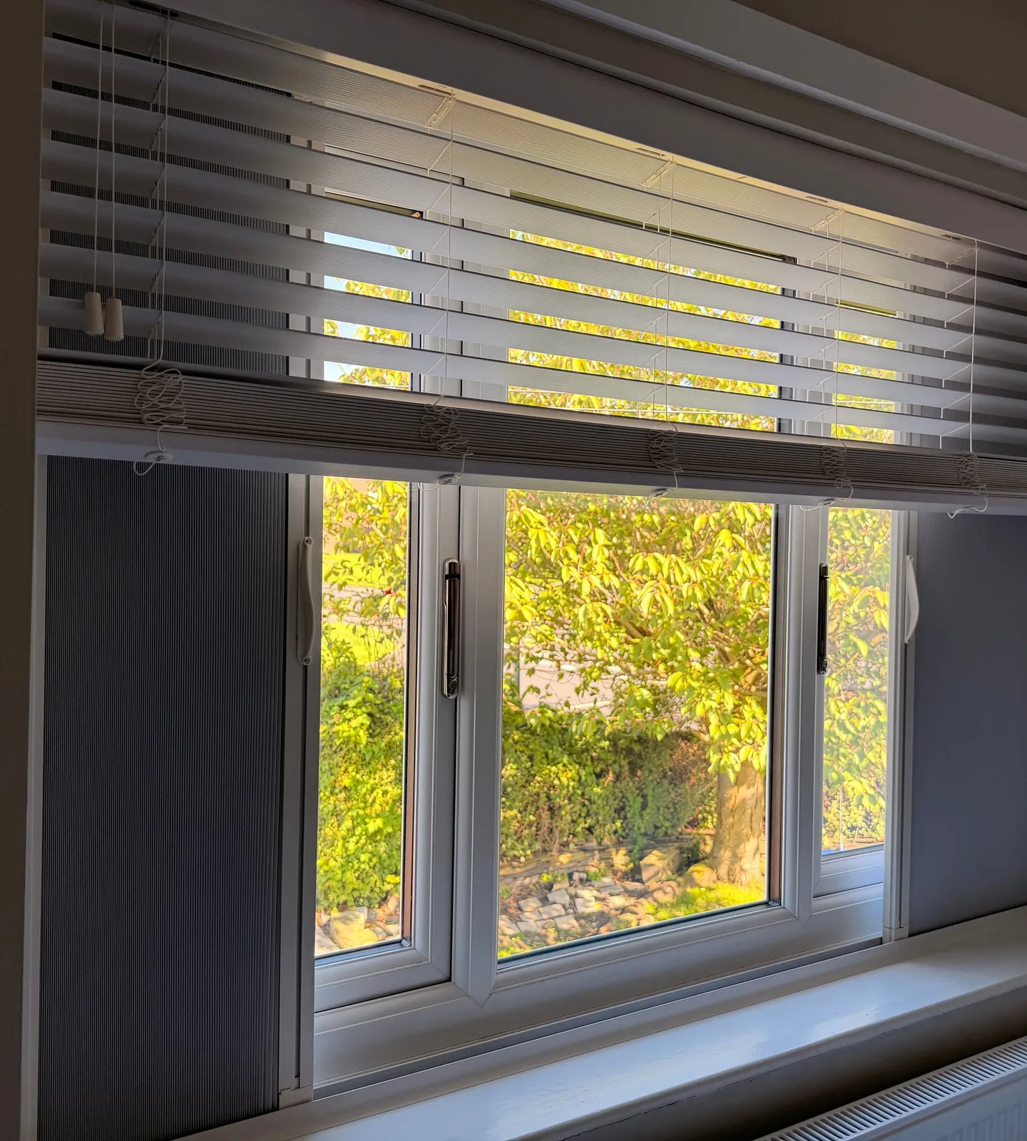 Blind Screen blackout screens parked at each side of a bedroom window beneath a white Venetian blind