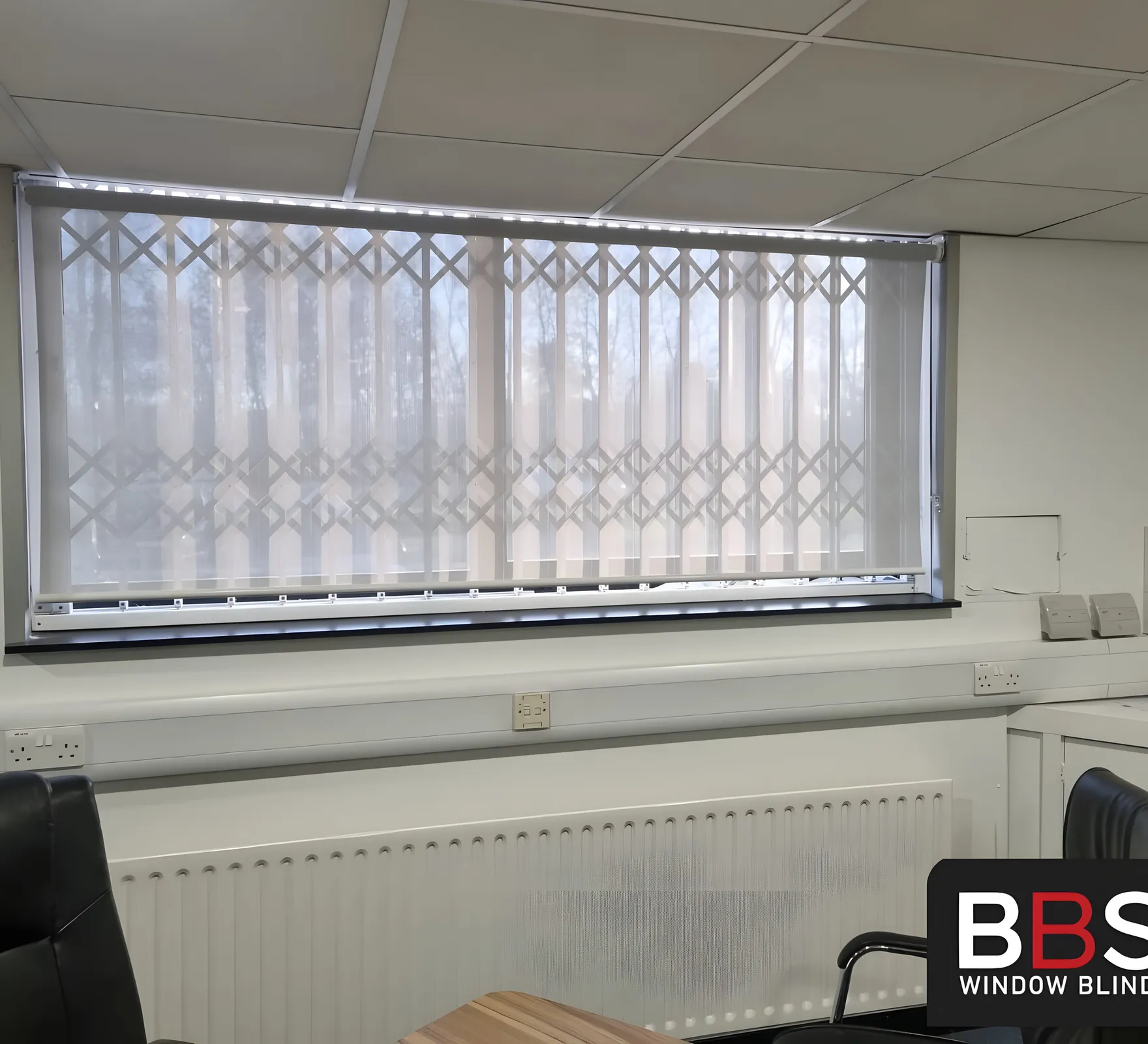 The old vertical blinds at Building Technology Systems before replacement, slats twisted and light breaking through unevenly