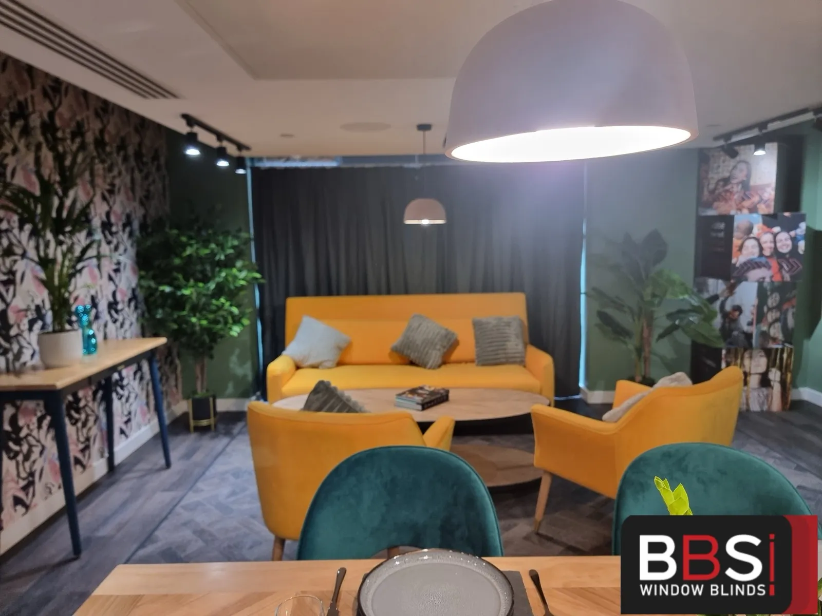 Resident lounge at Cale Cross with curtains drawn behind yellow armchairs and a dining table