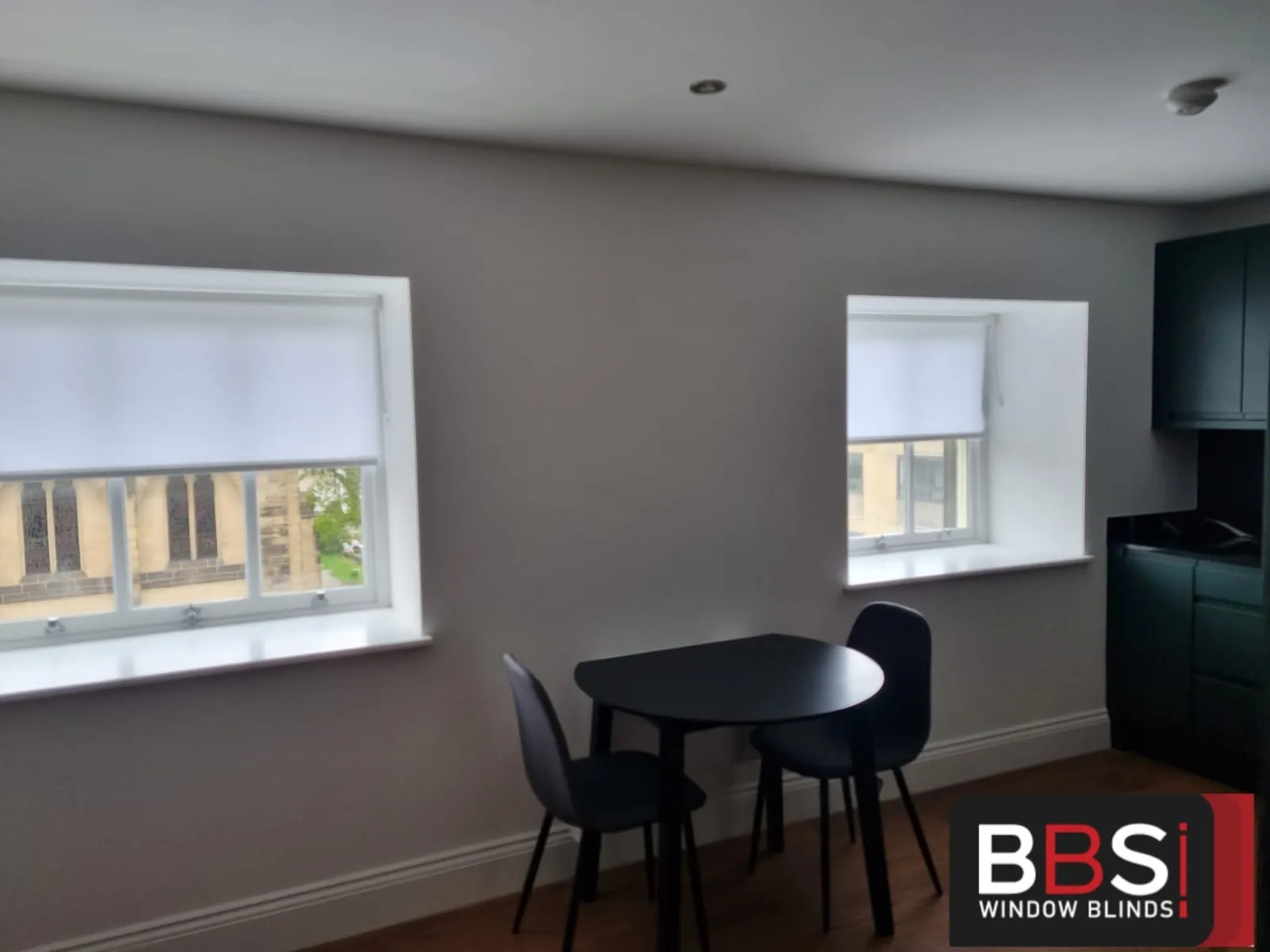 Light roller blinds part lowered on two windows of an open-plan kitchen and dining area at Cathedral View, Sheffield