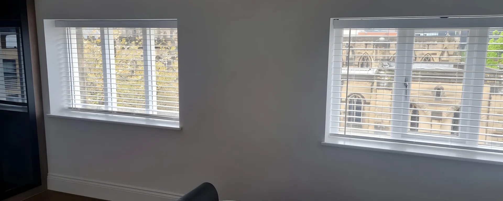 White Venetian blinds fitted to two windows of a new apartment at Cathedral View in Sheffield, exposed timber beam above the bed