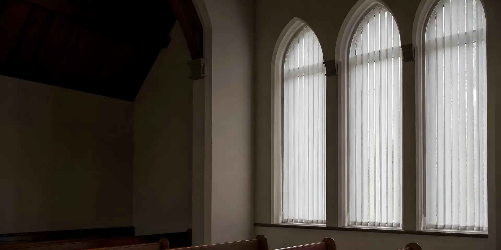 Vertical blinds fitted to tall windows in a British church interior