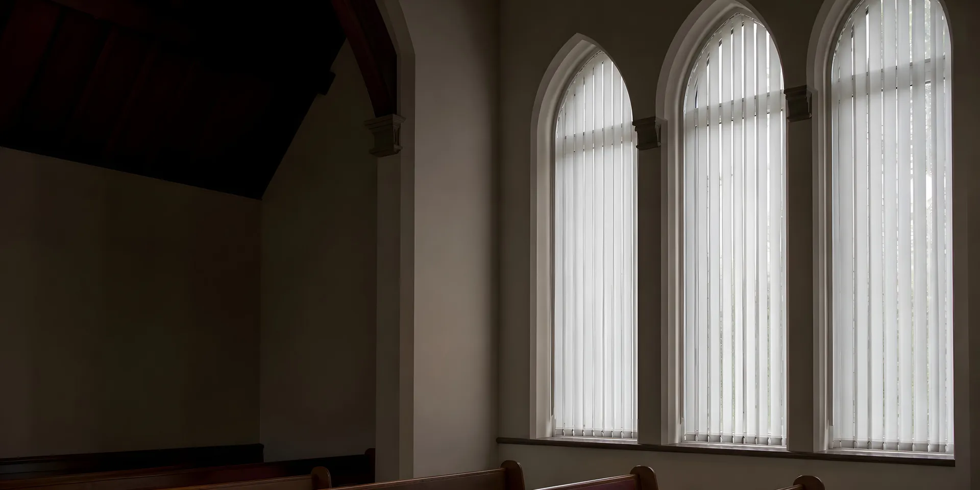 Vertical blinds fitted to tall windows in a British church interior