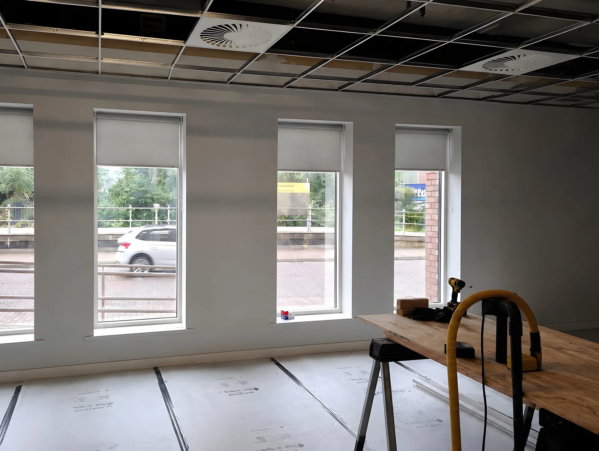 Grey roller blinds fitted across a run of commercial office windows