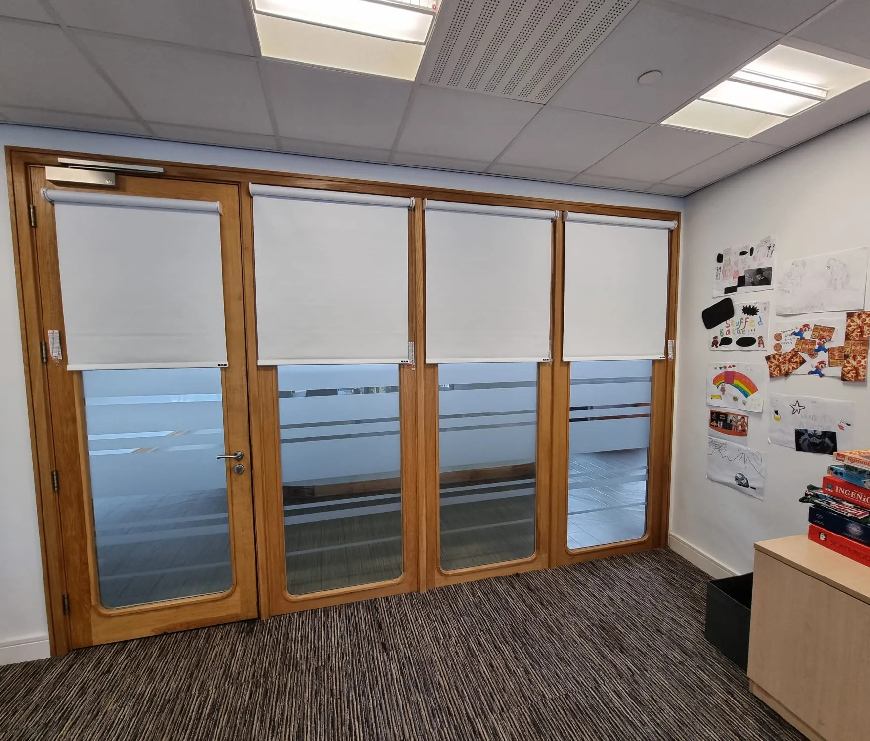 White roller blinds on oak-framed internal windows and a glazed door looking onto the hallway at Elms Bank College Hub