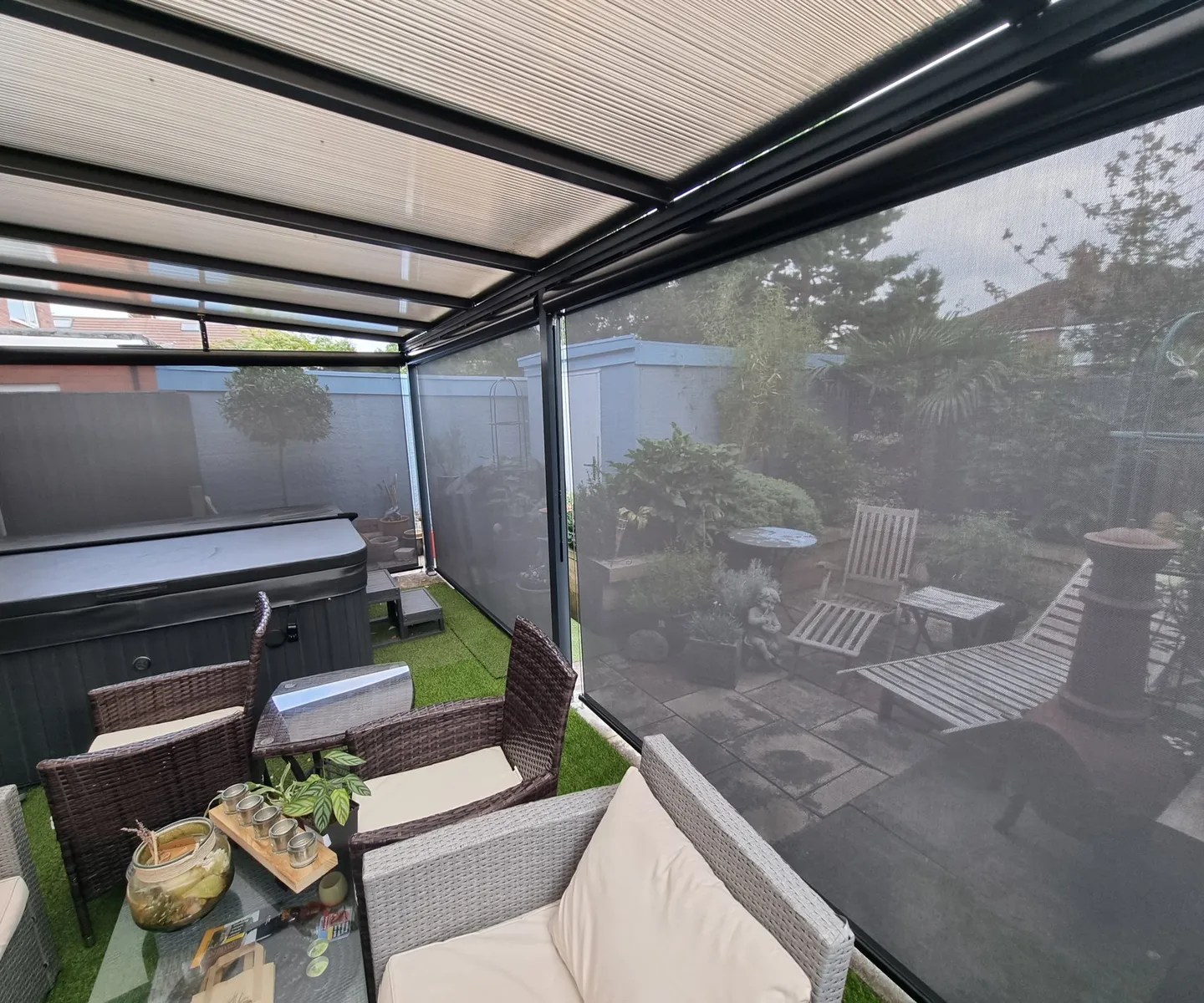 Grey external screen blinds lowered on a garden pergola beside a hot tub and seating