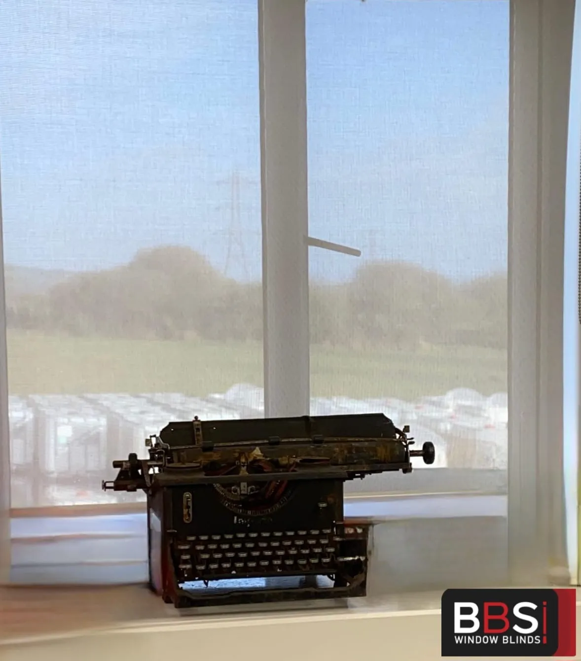 Close view of screen fabric at Faith House, Radcliffe, with daylight through the weave and a vintage typewriter on the sill