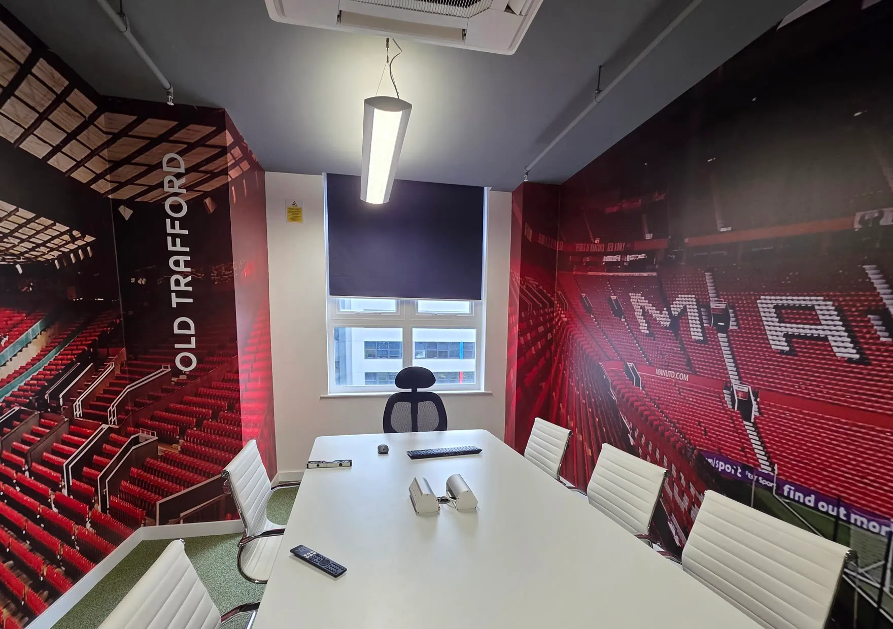 A navy roller blind in the Old Trafford themed meeting room at Global Banking School, with stadium wall graphics either side of the window