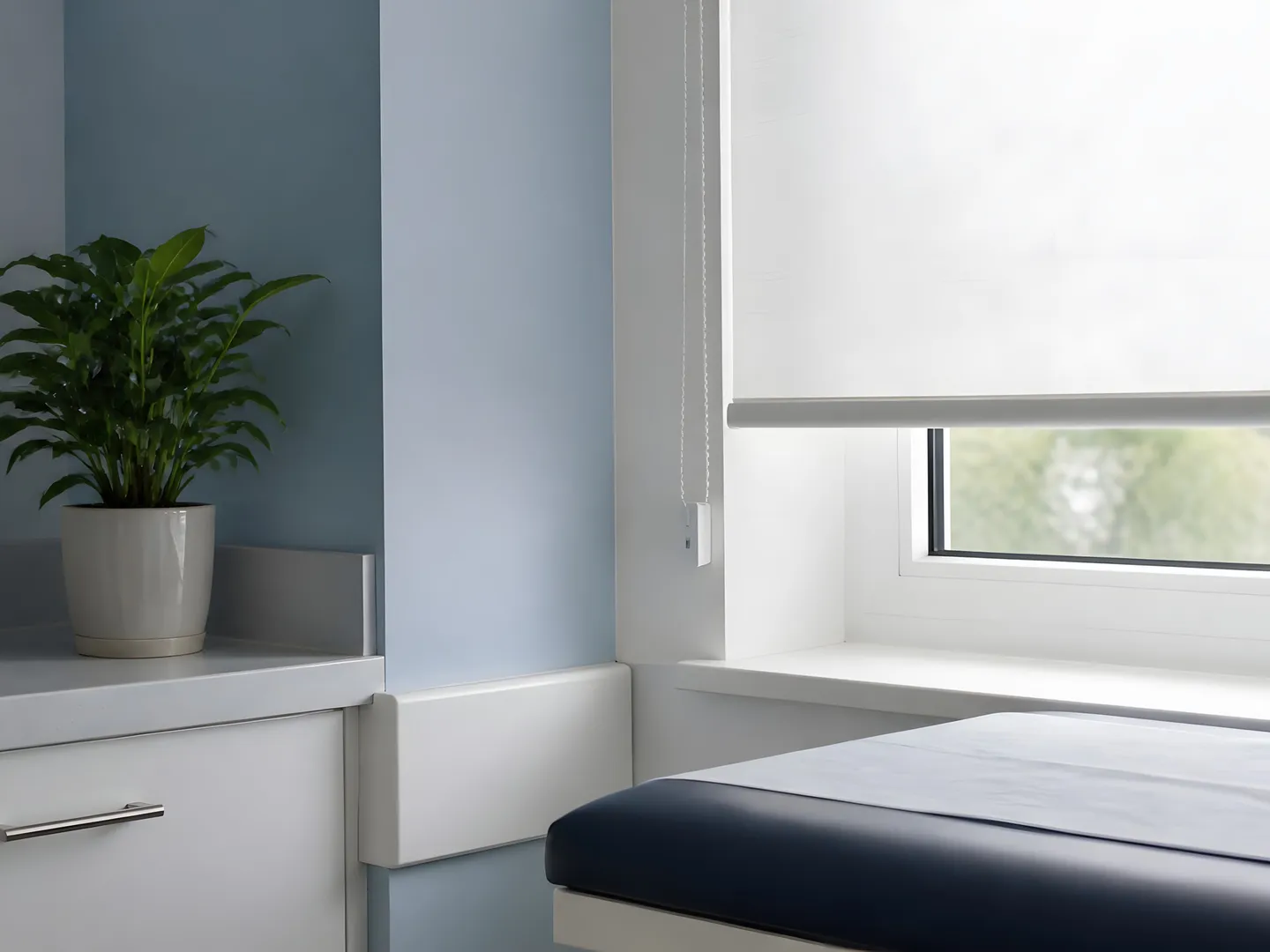 Pale roller blind beside a clean healthcare examination couch