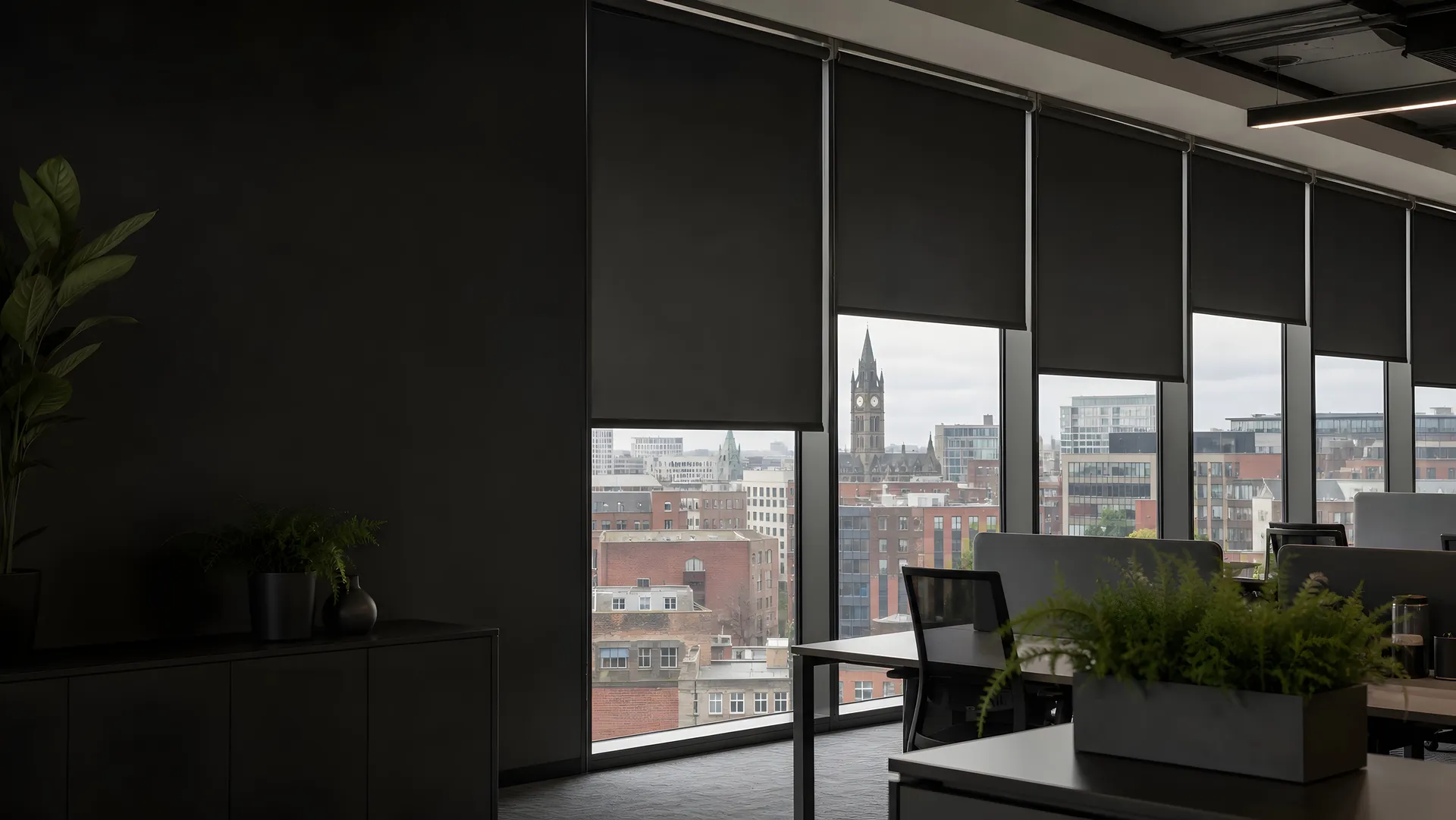 Office interior with dark roller blinds, looking out over central Manchester
