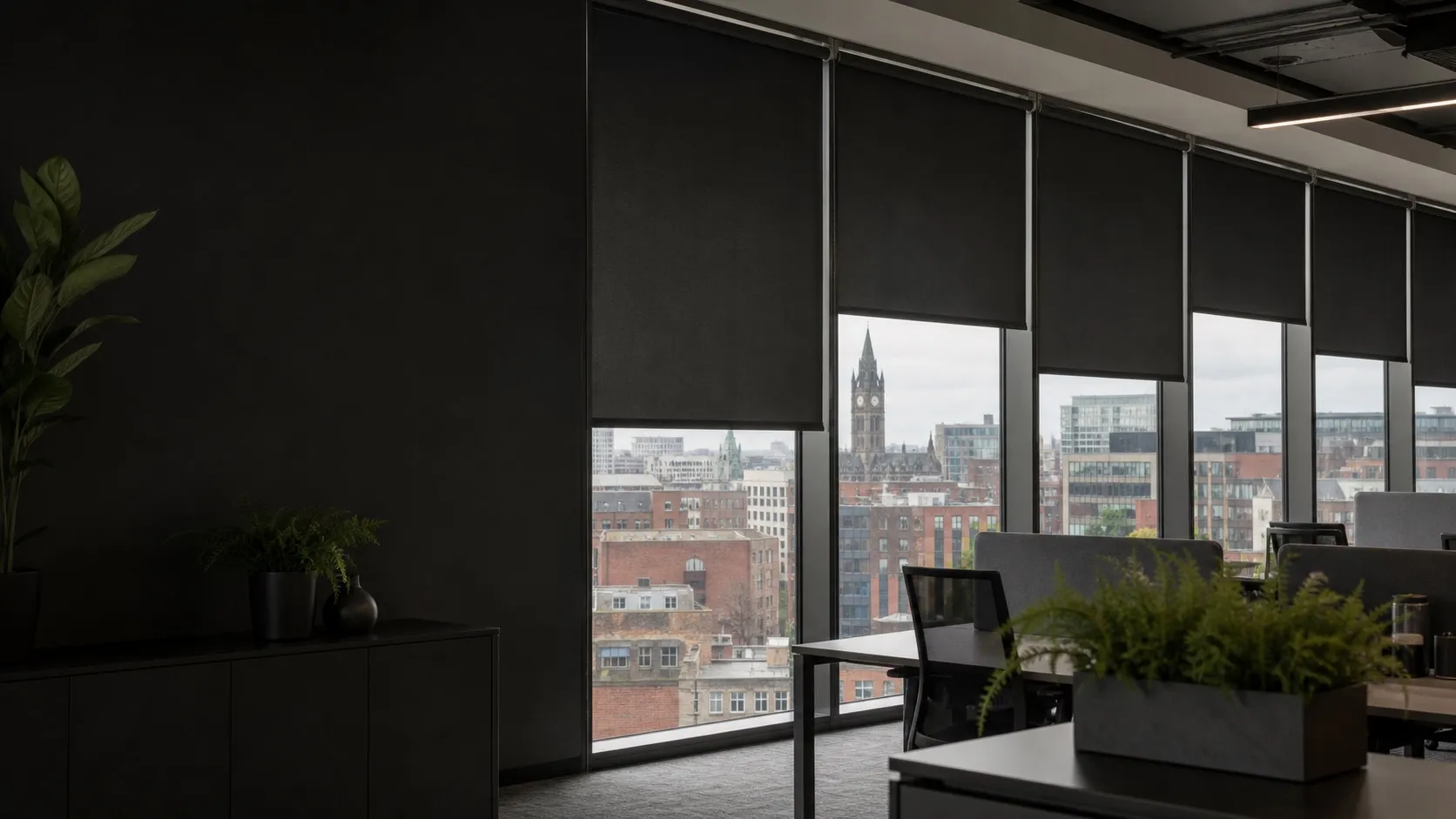 Office interior with dark roller blinds, looking out over central Manchester