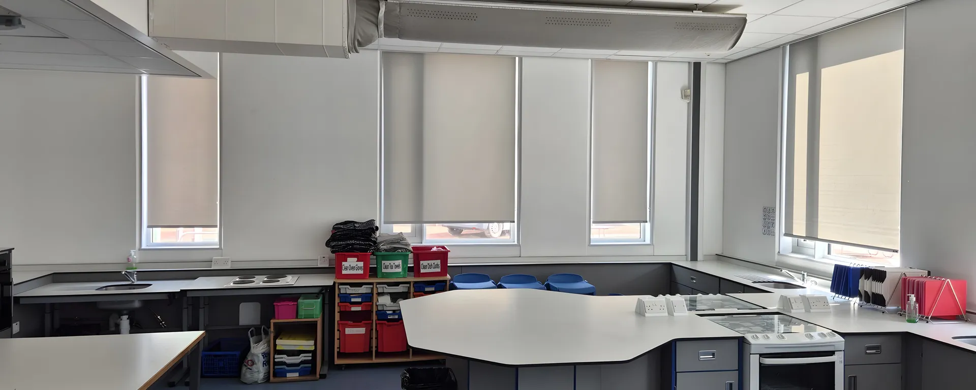 Food technology room at Irlam and Cadishead High School with roller blinds along the window wall beneath the extraction canopy