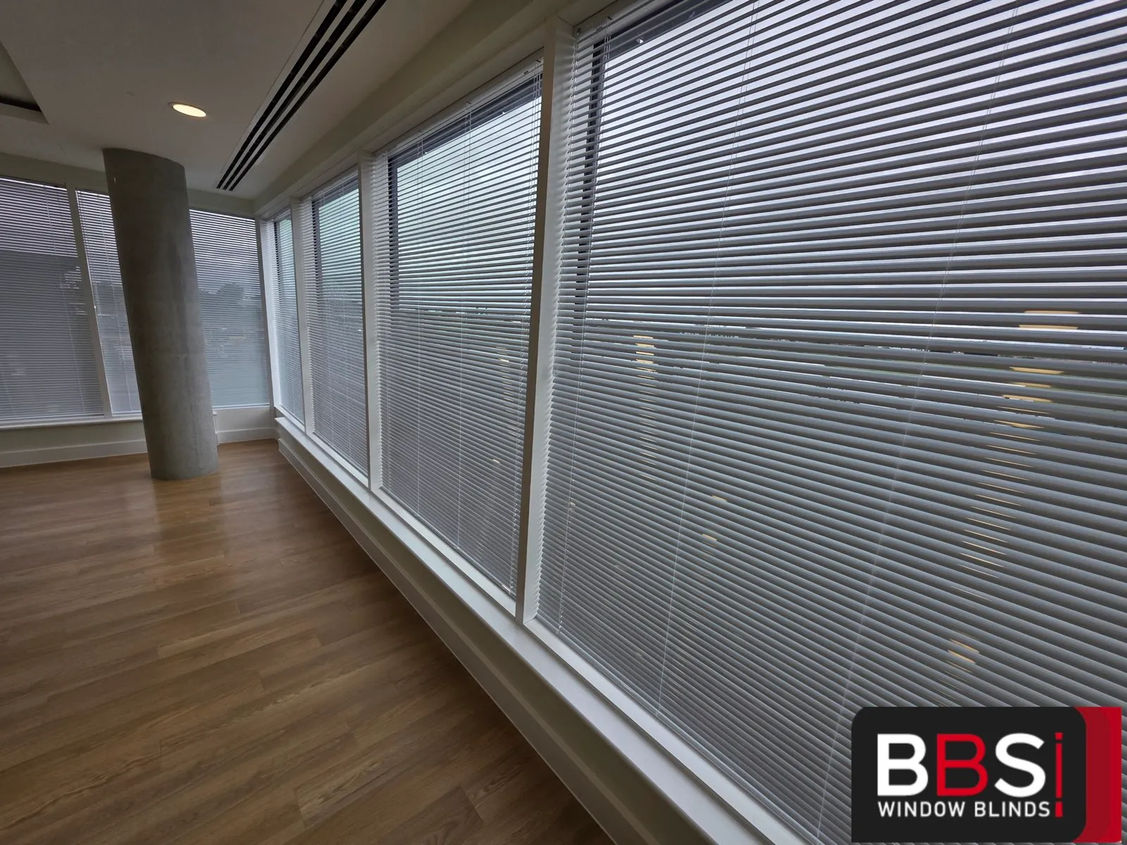 Run of white aluminium venetian blinds fitted to the curtain walling on an upper floor