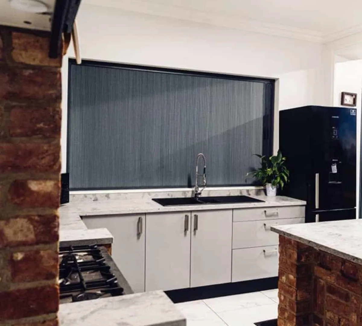 Dark grey Blind Screen honeycomb blind drawn across a wide kitchen window above the sink
