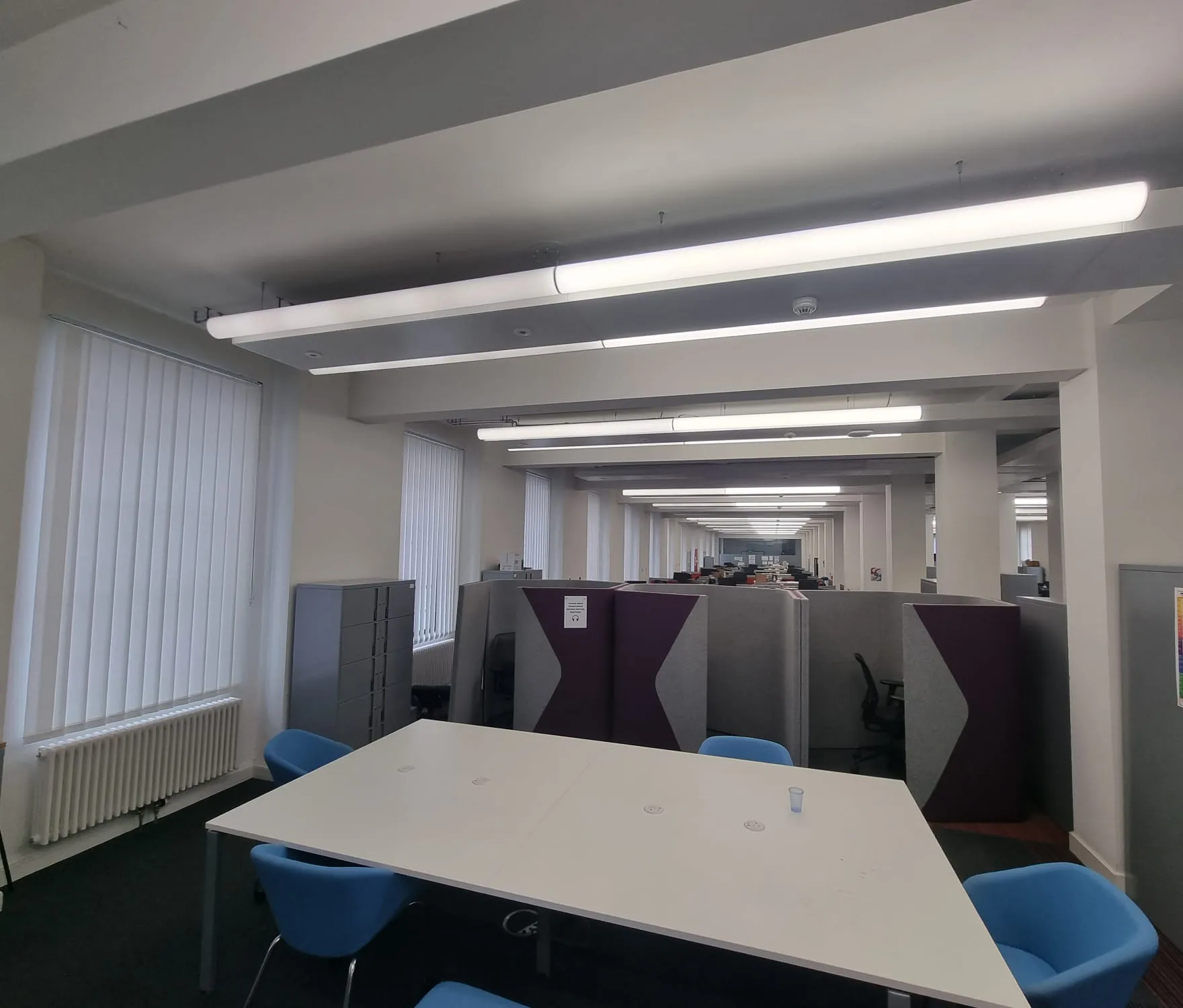 White vertical blinds on Manchester Town Hall offices, looking down the open-plan floor from a meeting table