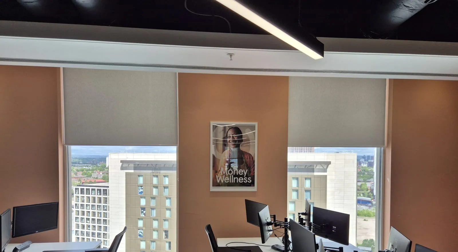 Roller blinds fitted across the windows of a finished office at Salford Quays, Manchester skyline behind