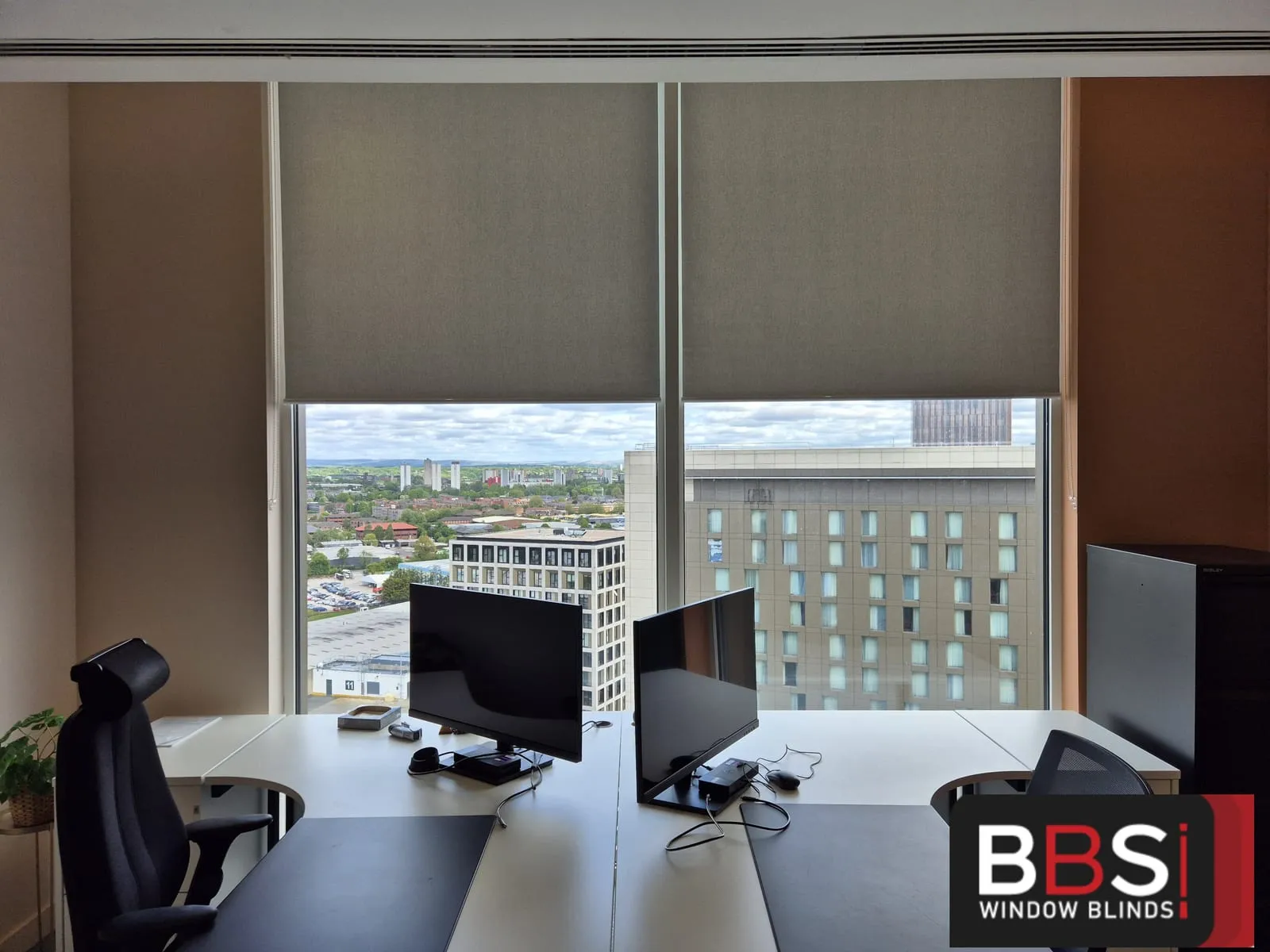 Warm neutral screen fabric blinds across two oversized panes at Money Wellness, terracotta wall between them and the city view below
