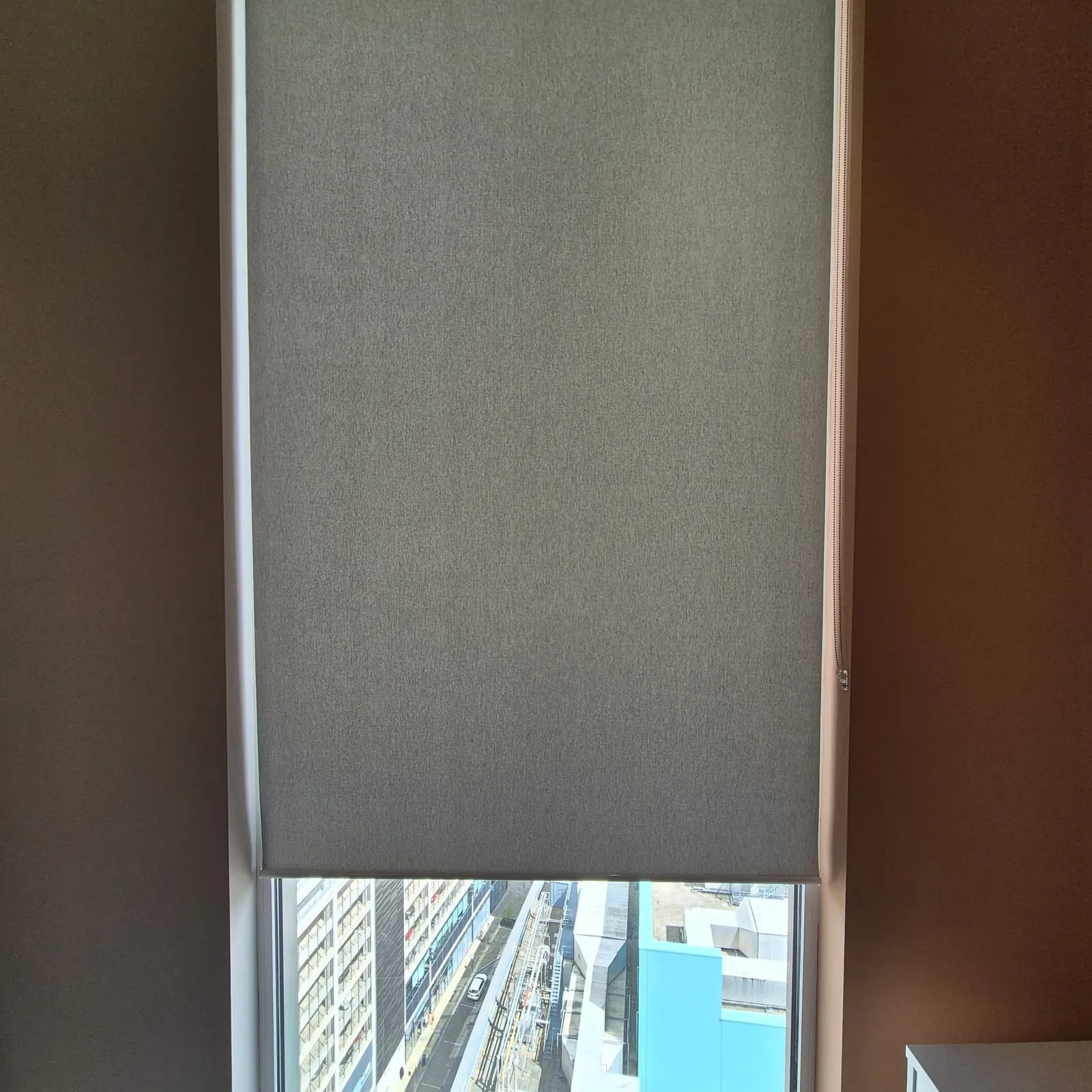 A single full-height screen fabric roller blind at Money Wellness with the Salford Quays towers visible through the weave