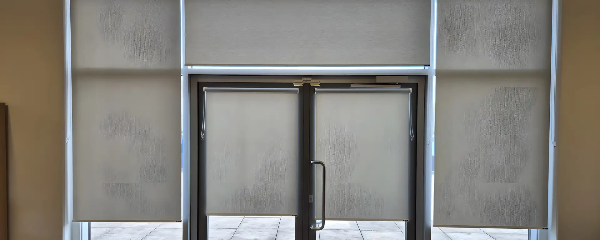 Wall of matching dim-out roller blinds either side of a glazed fire exit door at Moorside High School