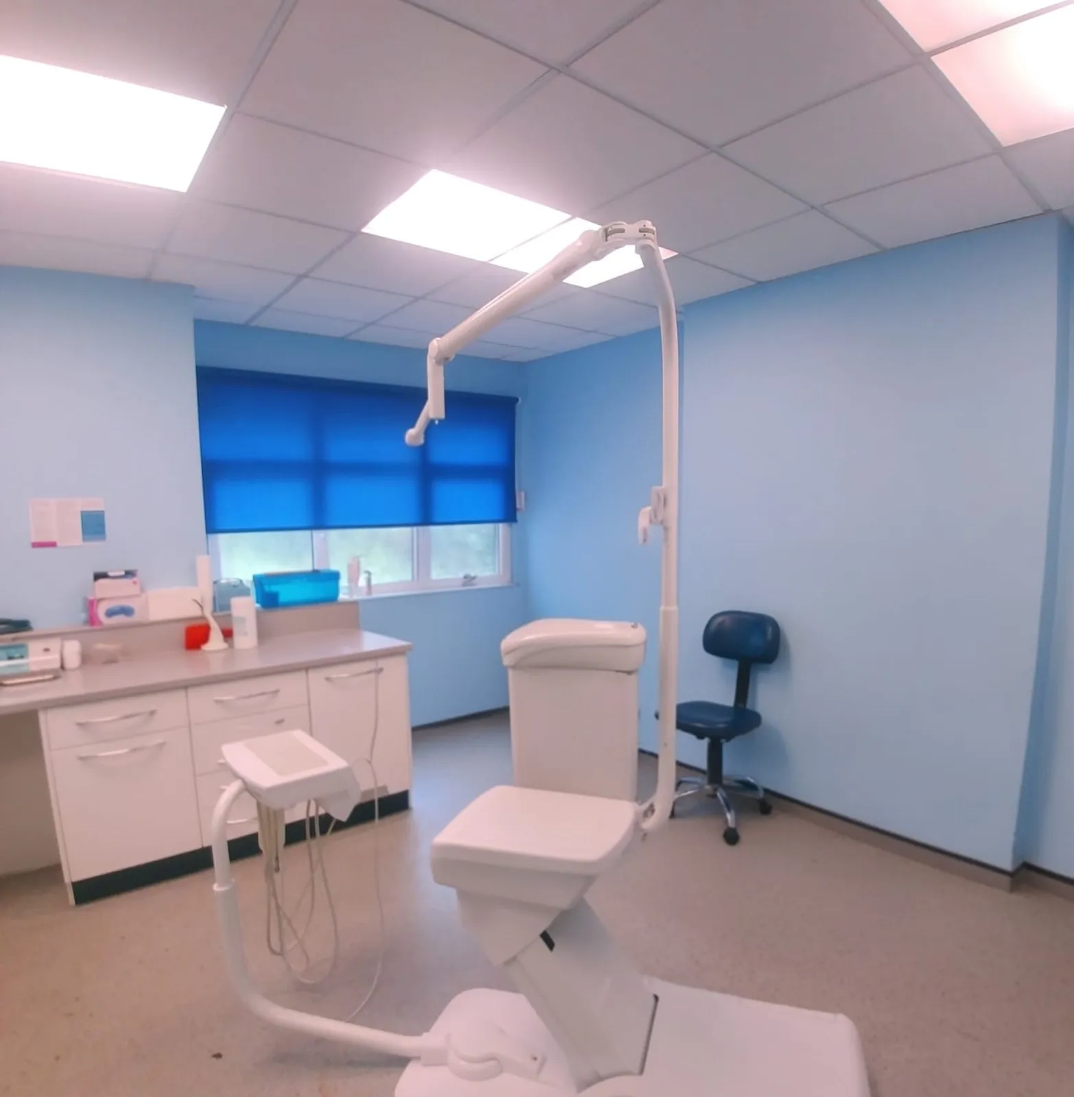 Bright blue roller blind on the window of a dental X-ray room, with the panoramic unit in the foreground