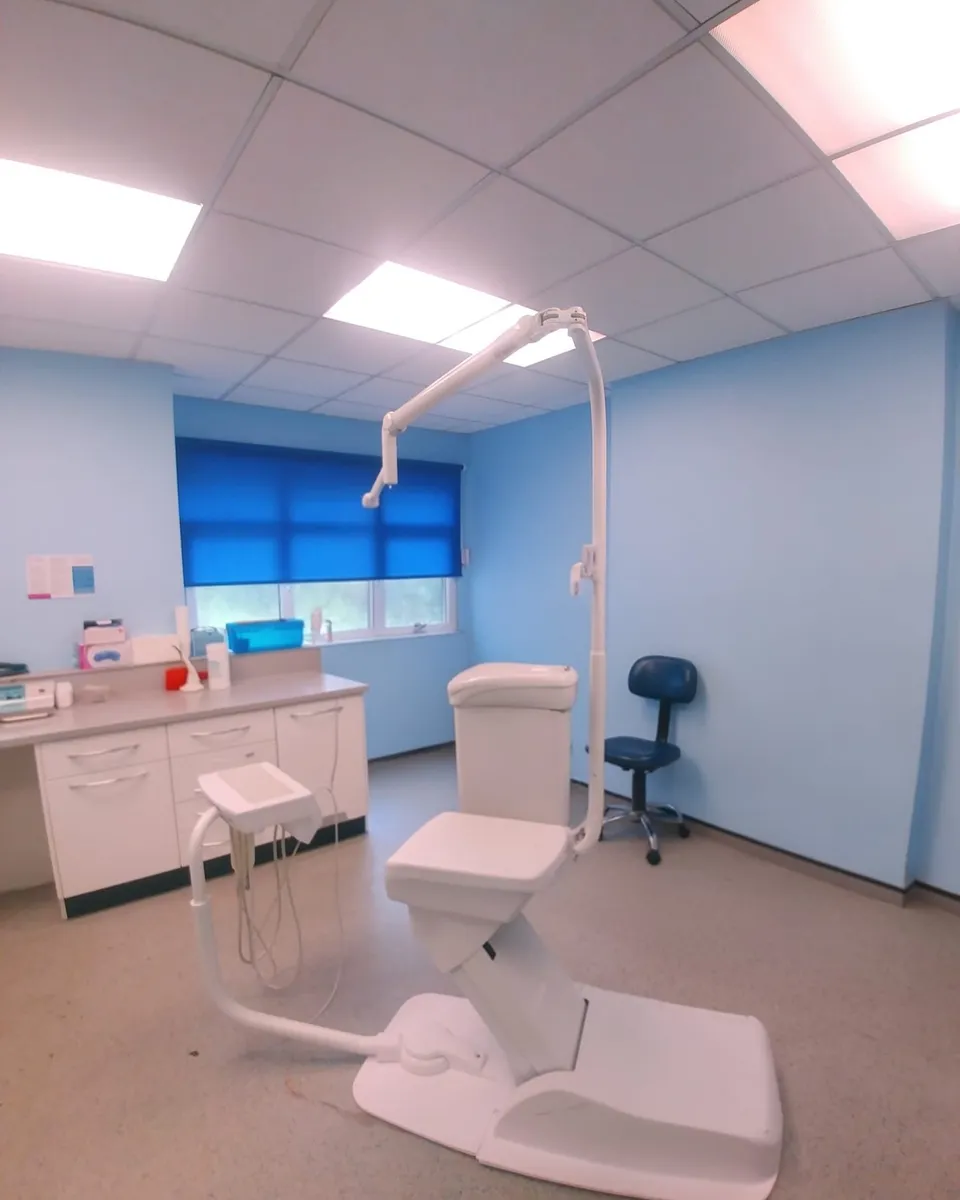 Blue roller blind across the window of a dental treatment room in North Manchester, dental chair and cabinets in front