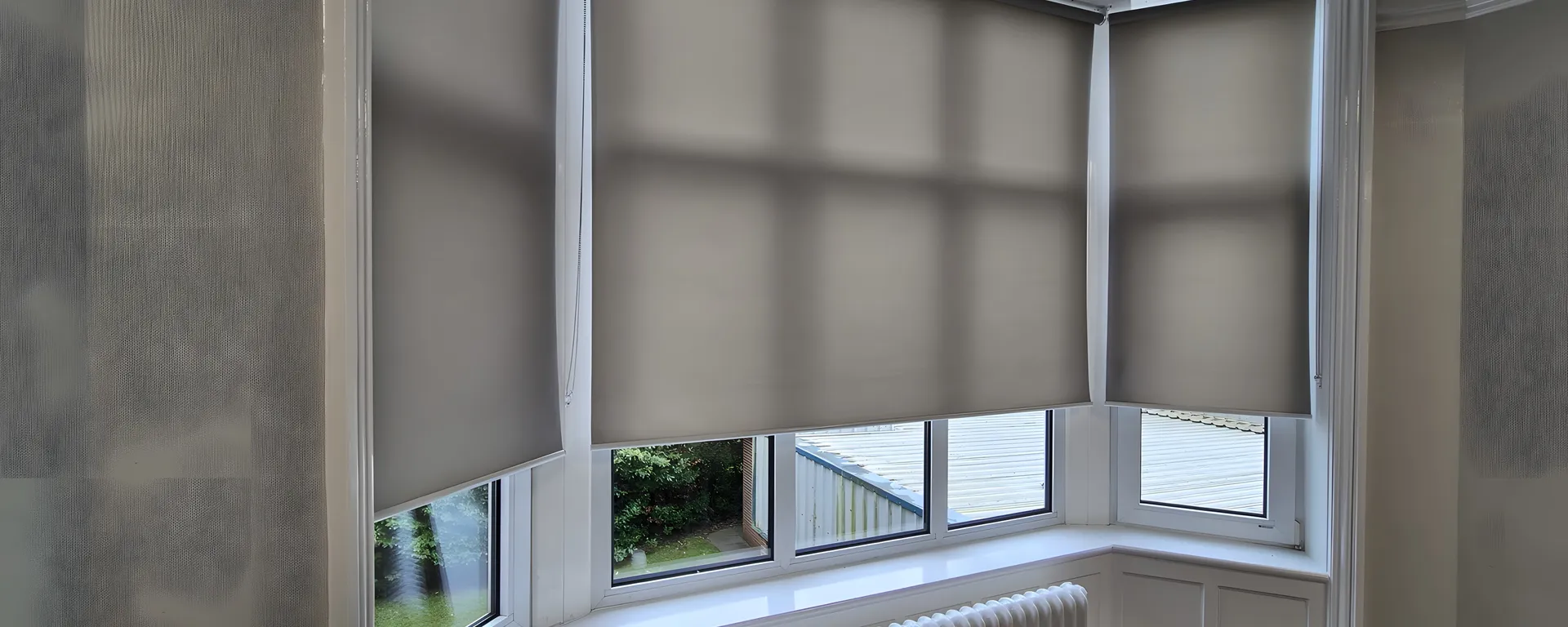 Bay window at North West Ambulance Service HQ fitted with a run of matching neutral roller blinds