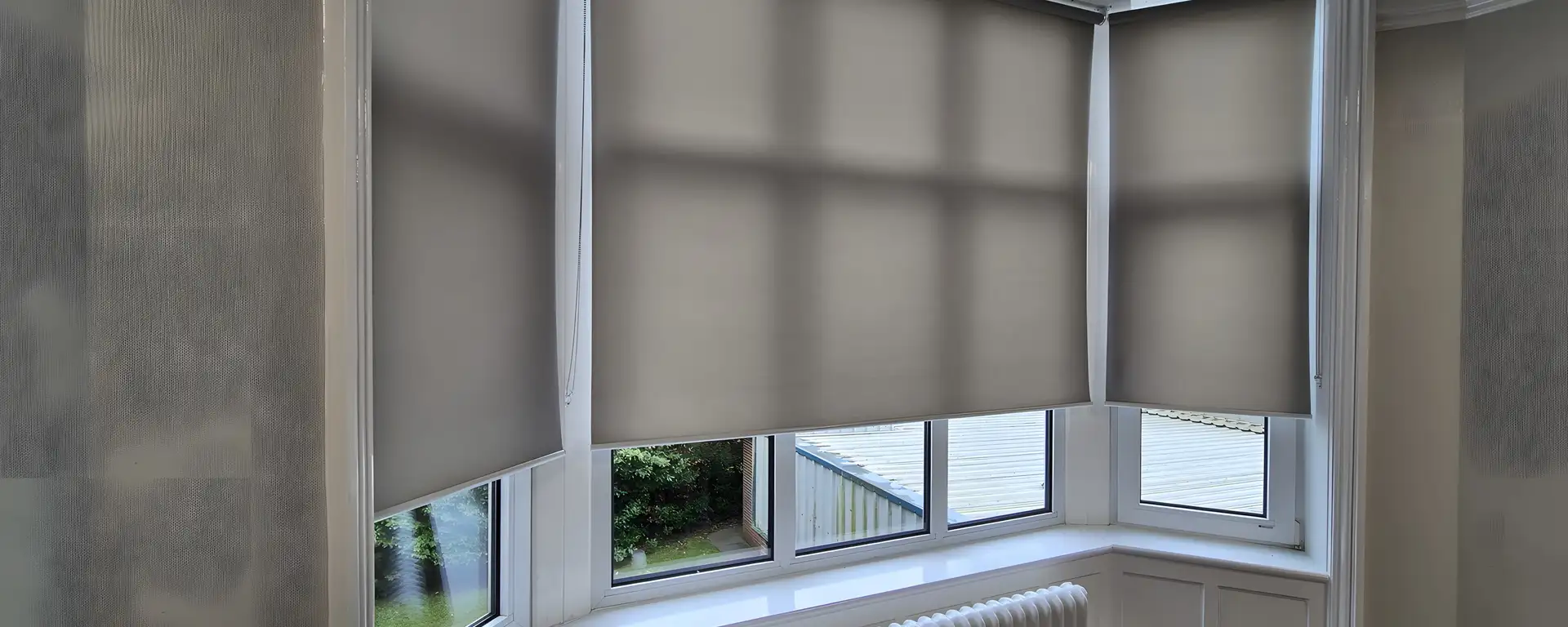 Bay window at North West Ambulance Service HQ fitted with a run of matching neutral roller blinds