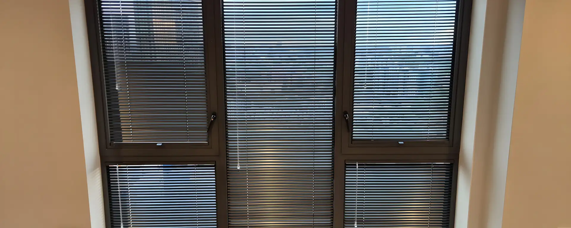 Black Perfect Fit Venetian blinds fitted to a three-panel window in a Manchester apartment