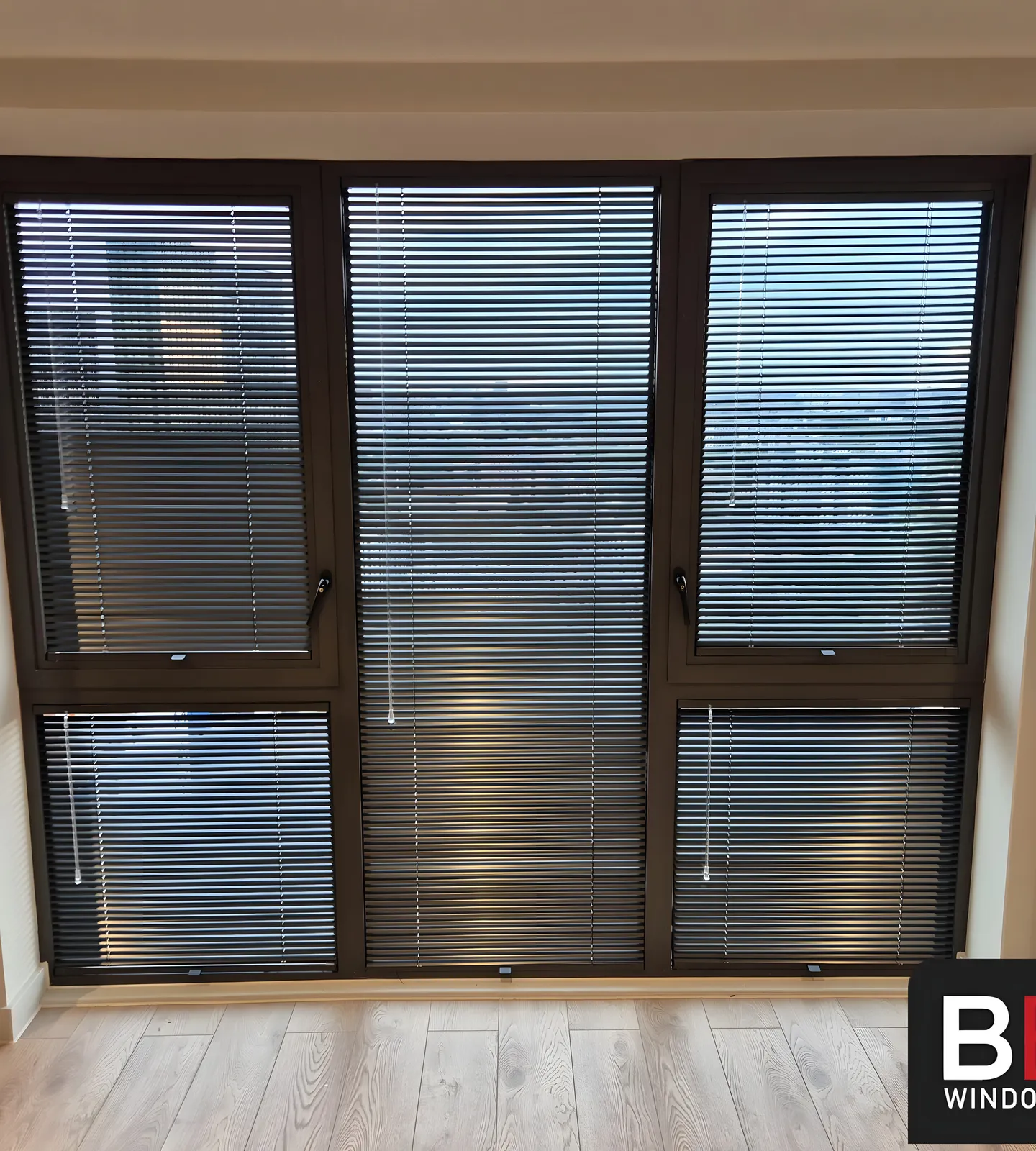 Black Perfect Fit Venetian blinds fitted to a three-panel window in a Manchester apartment