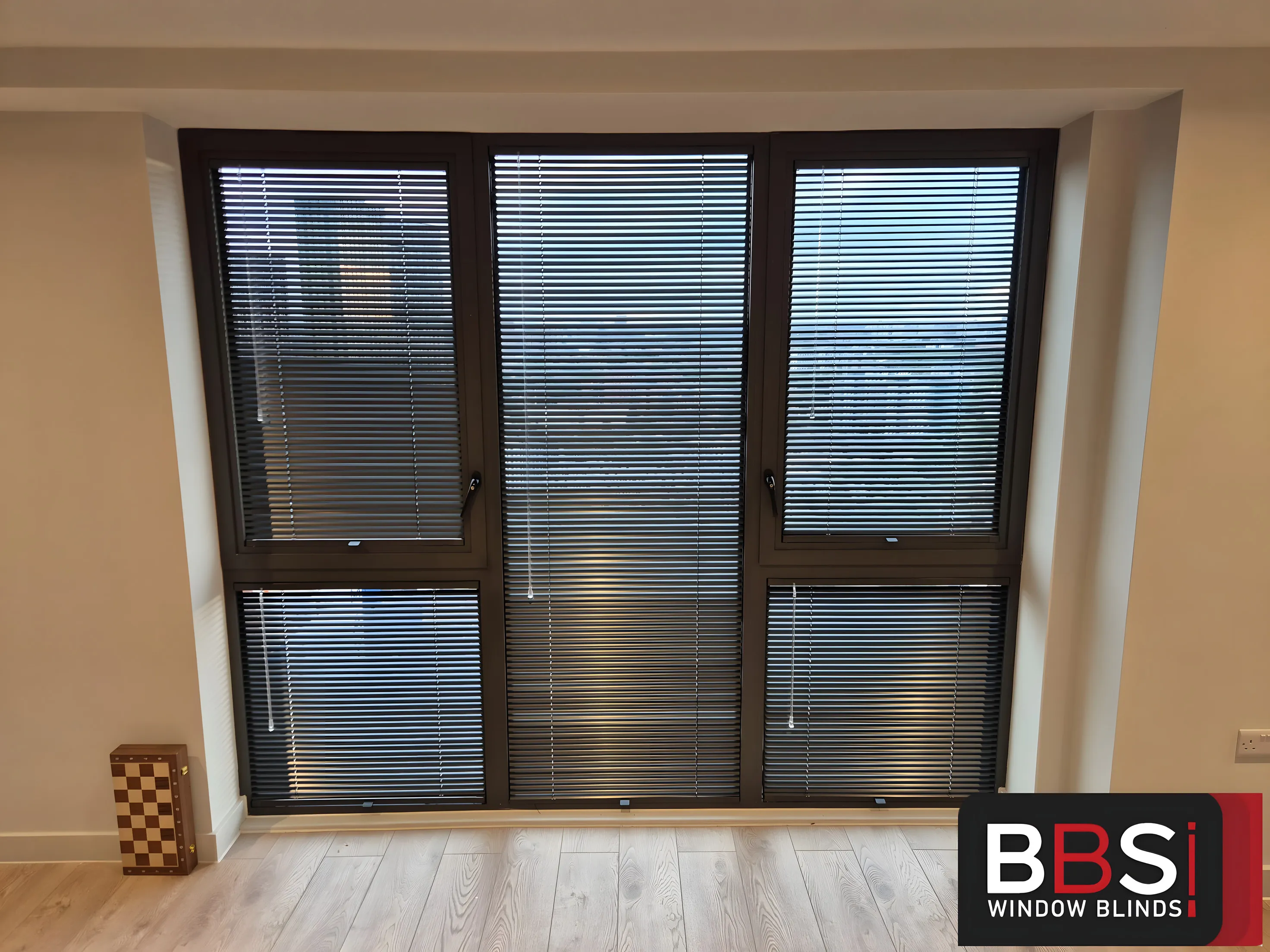 Black Perfect Fit Venetian blinds fitted to a three-panel window in a Manchester apartment