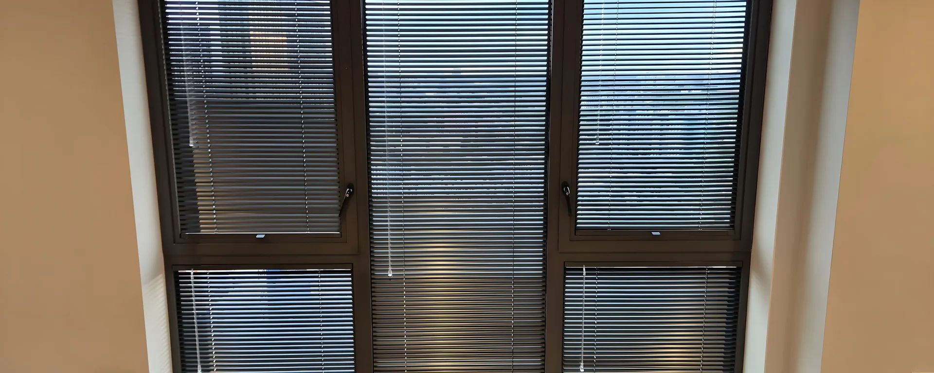 Black Perfect Fit Venetian blinds fitted to a three-panel window in a Manchester apartment