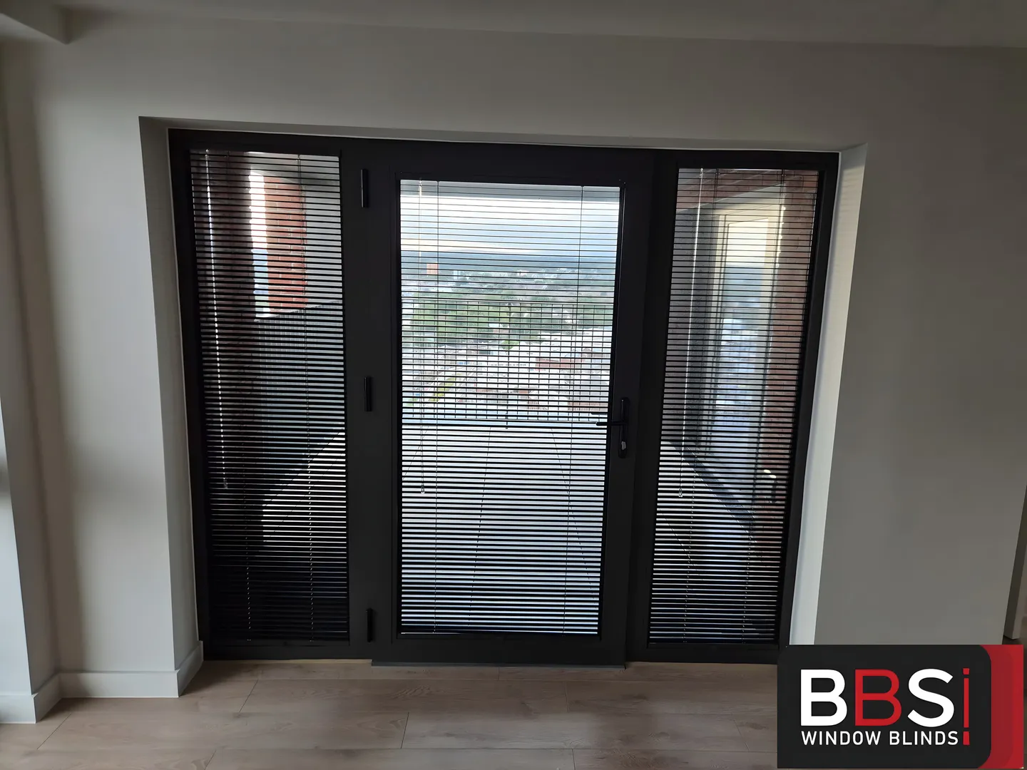 Black Perfect Fit Venetian blinds on a high-rise apartment balcony door and side panels
