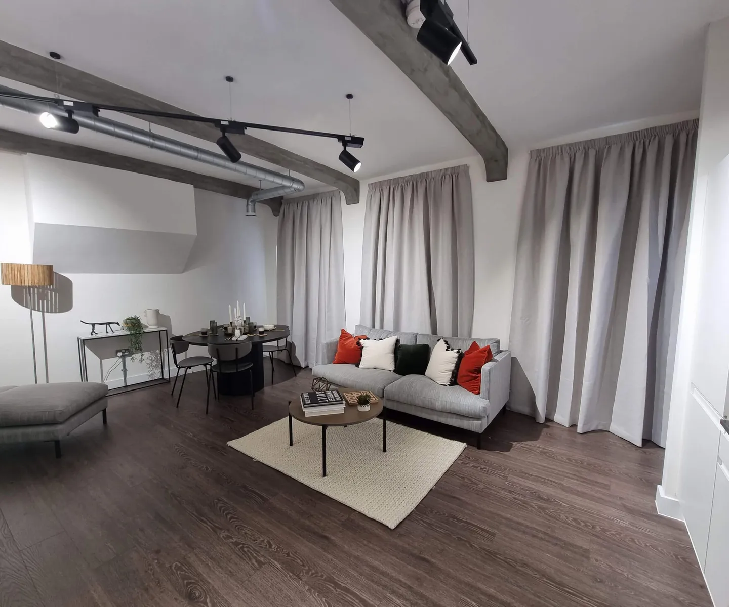 Full-length grey curtains beside a sofa and dining table in an open-plan apartment