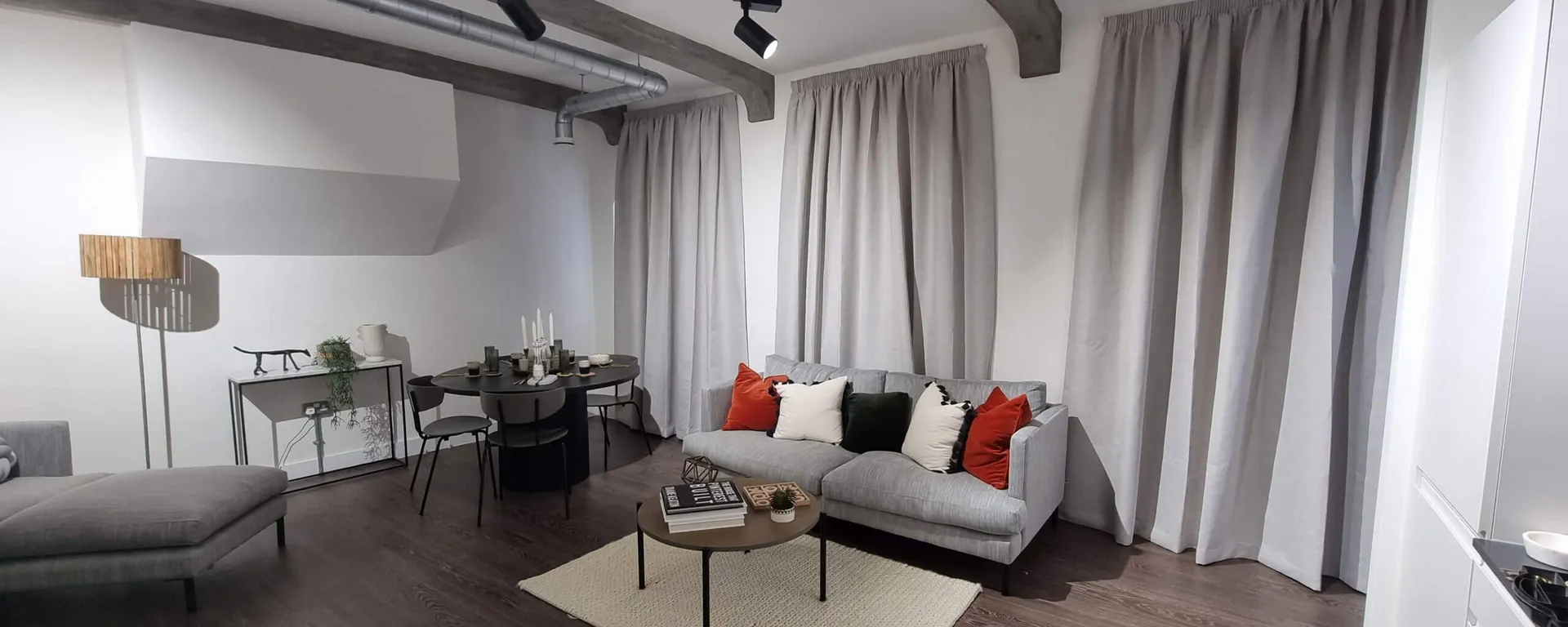 Full-length grey curtains fitted around a staged living and dining room