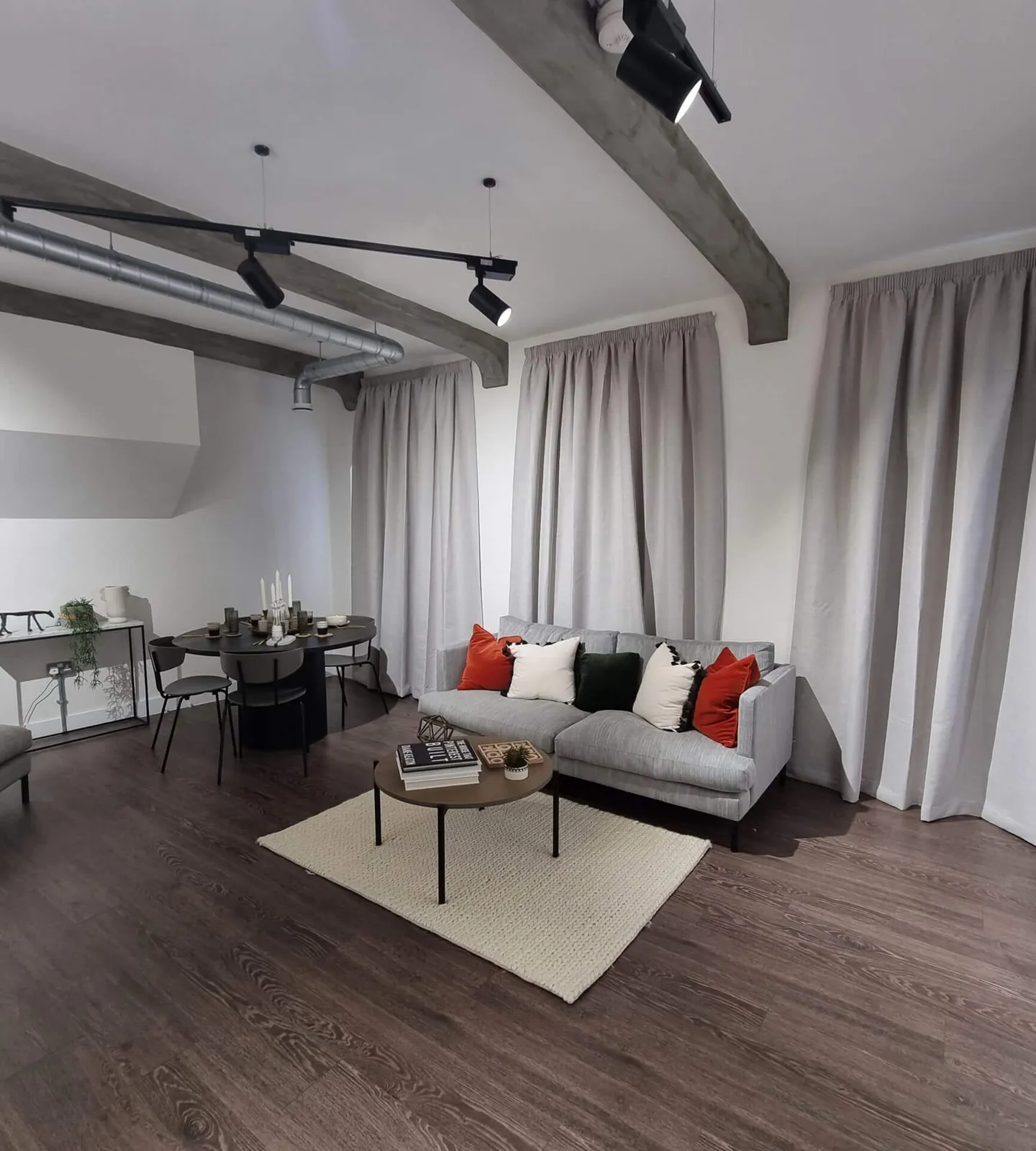 Full-length grey curtains beside a sofa and dining table in an open-plan apartment