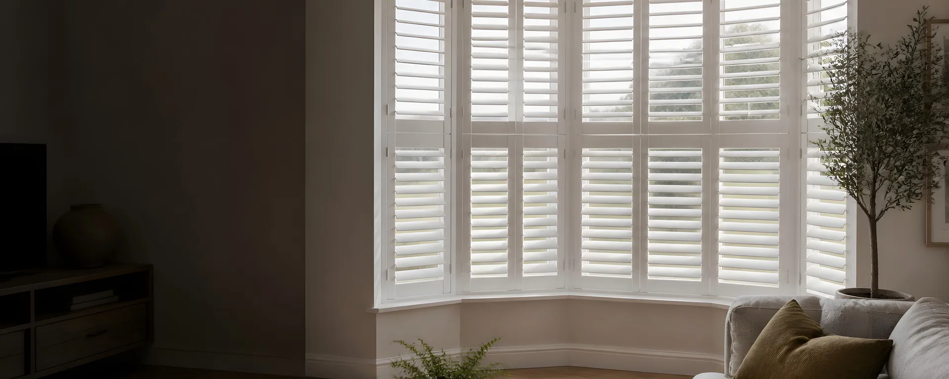 White interior shutters fitted across a bright bay window