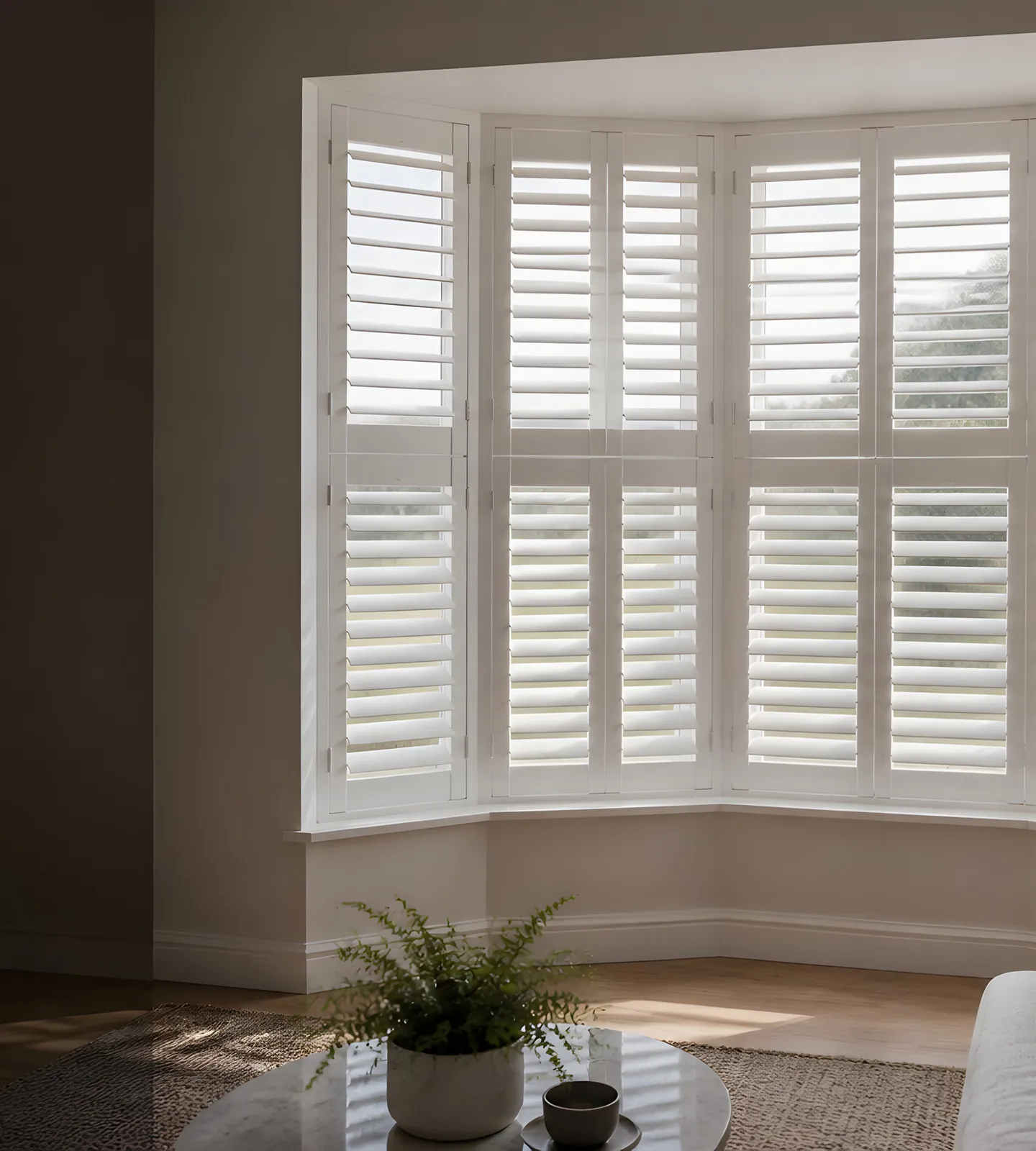 White interior shutters fitted across a bright bay window