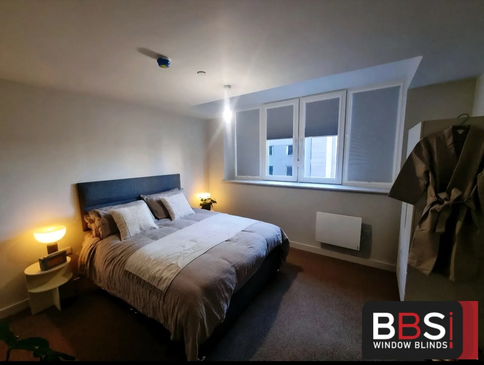 Bedroom at Rocco House with grey perfect fit pleated blinds fitted into the window frames above the bed