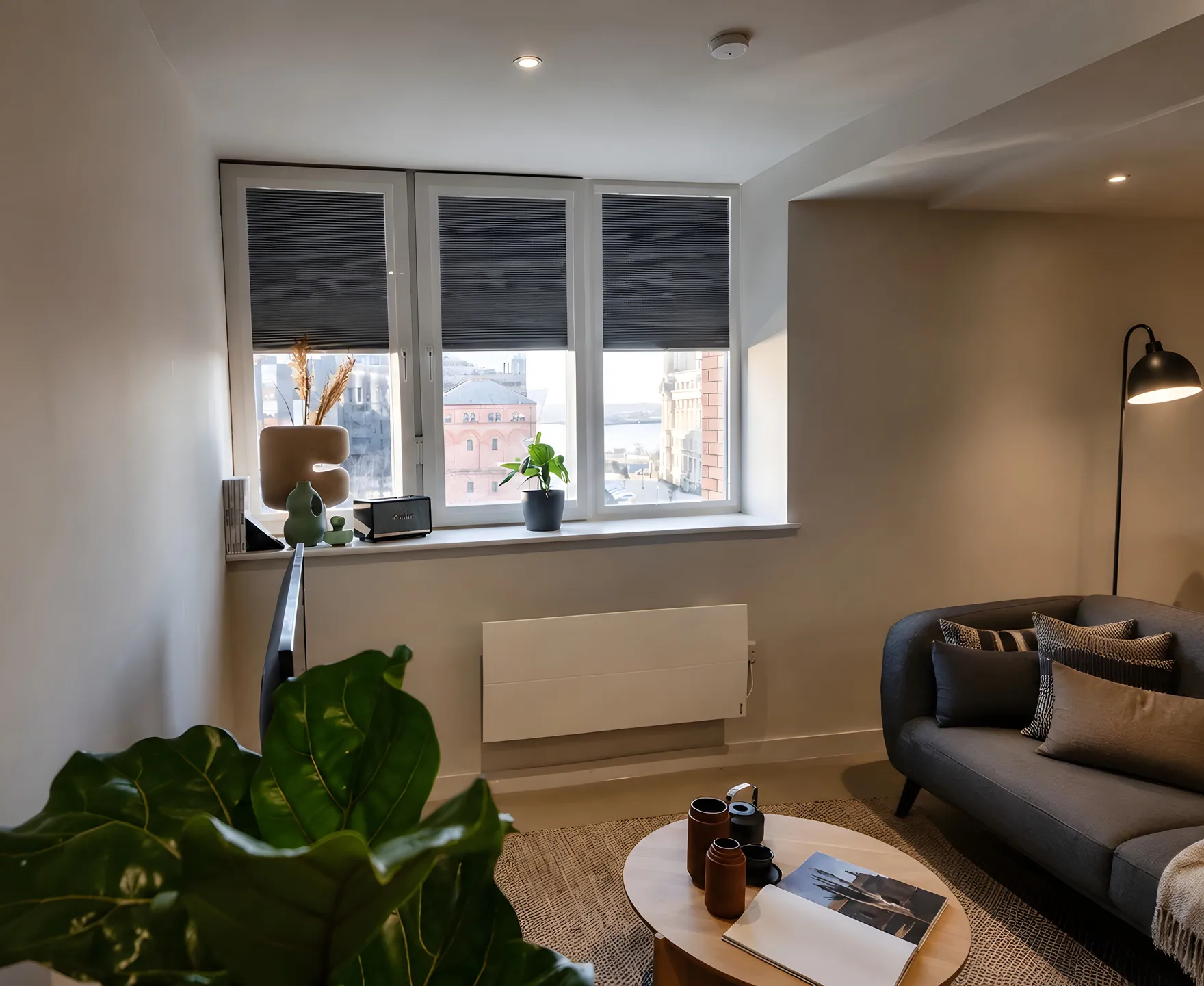 Grey perfect fit pleated blinds clipped into the UPVC window frames of a Rocco House apartment overlooking Liverpool