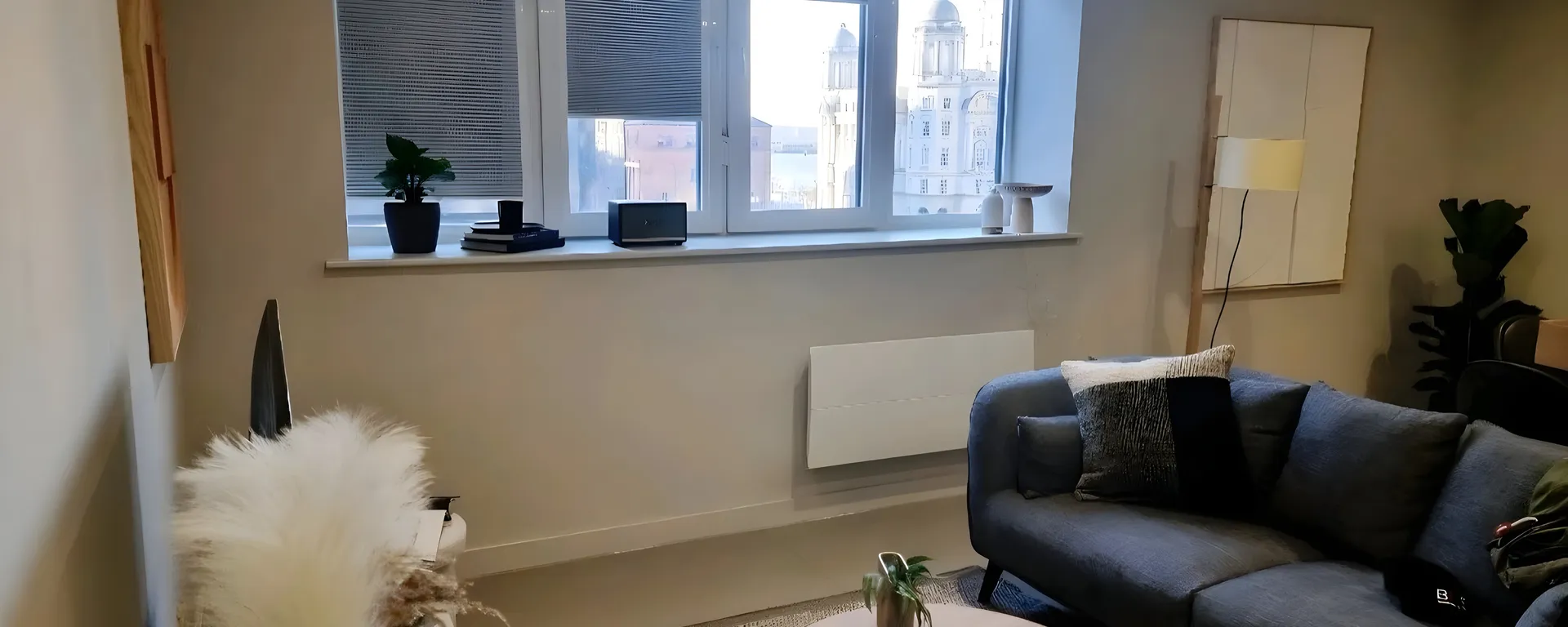 Grey perfect fit pleated blinds in a Rocco House apartment living room with the Liver Building visible through the window