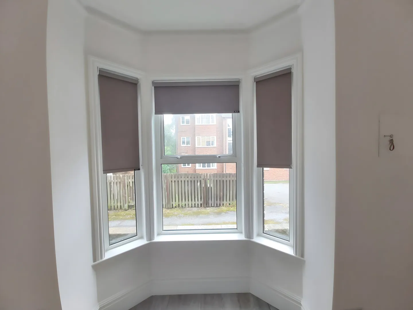 Three grey roller blinds fitted to the sash windows of a period bay