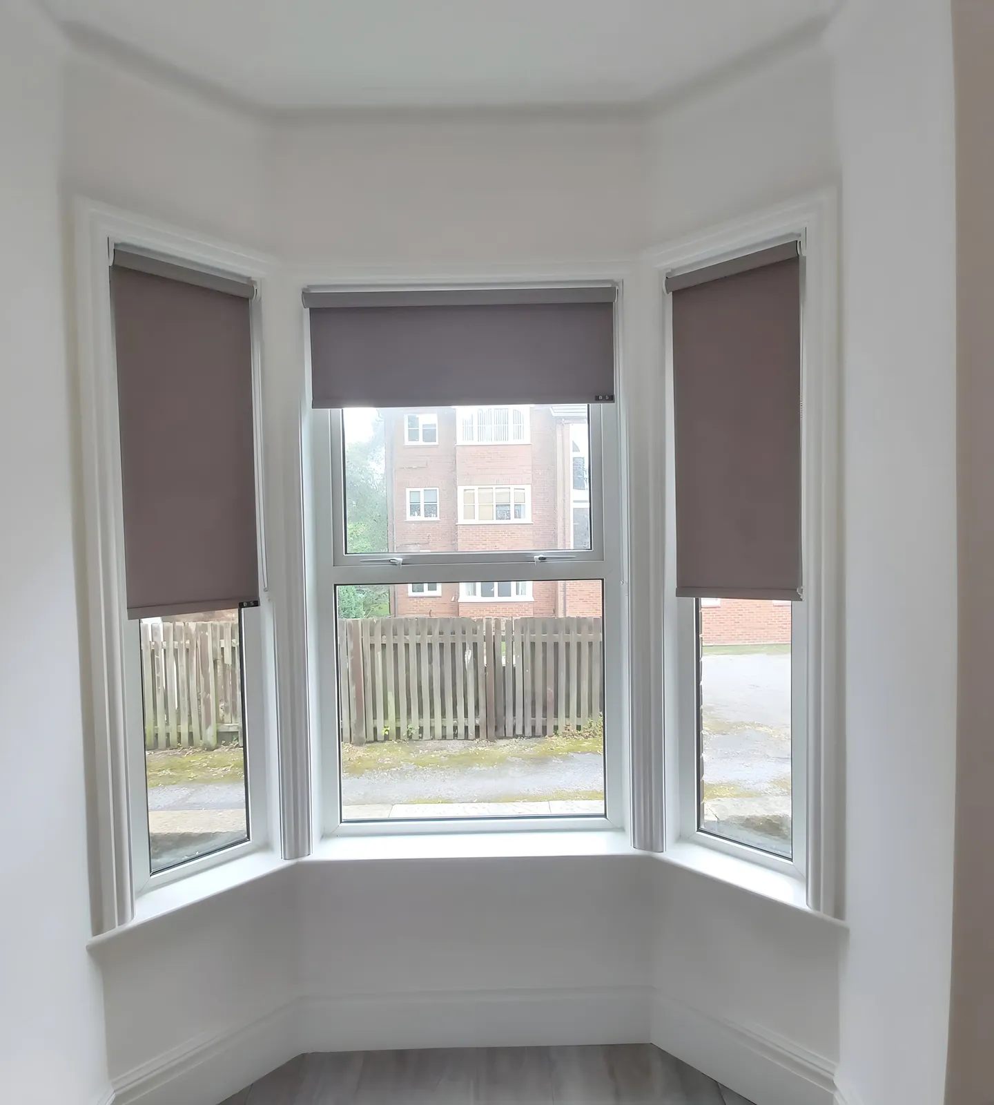 Three grey roller blinds fitted to the sash windows of a period bay