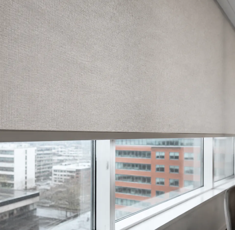 Neutral roller blind fitted across a wide window in a modern North West office