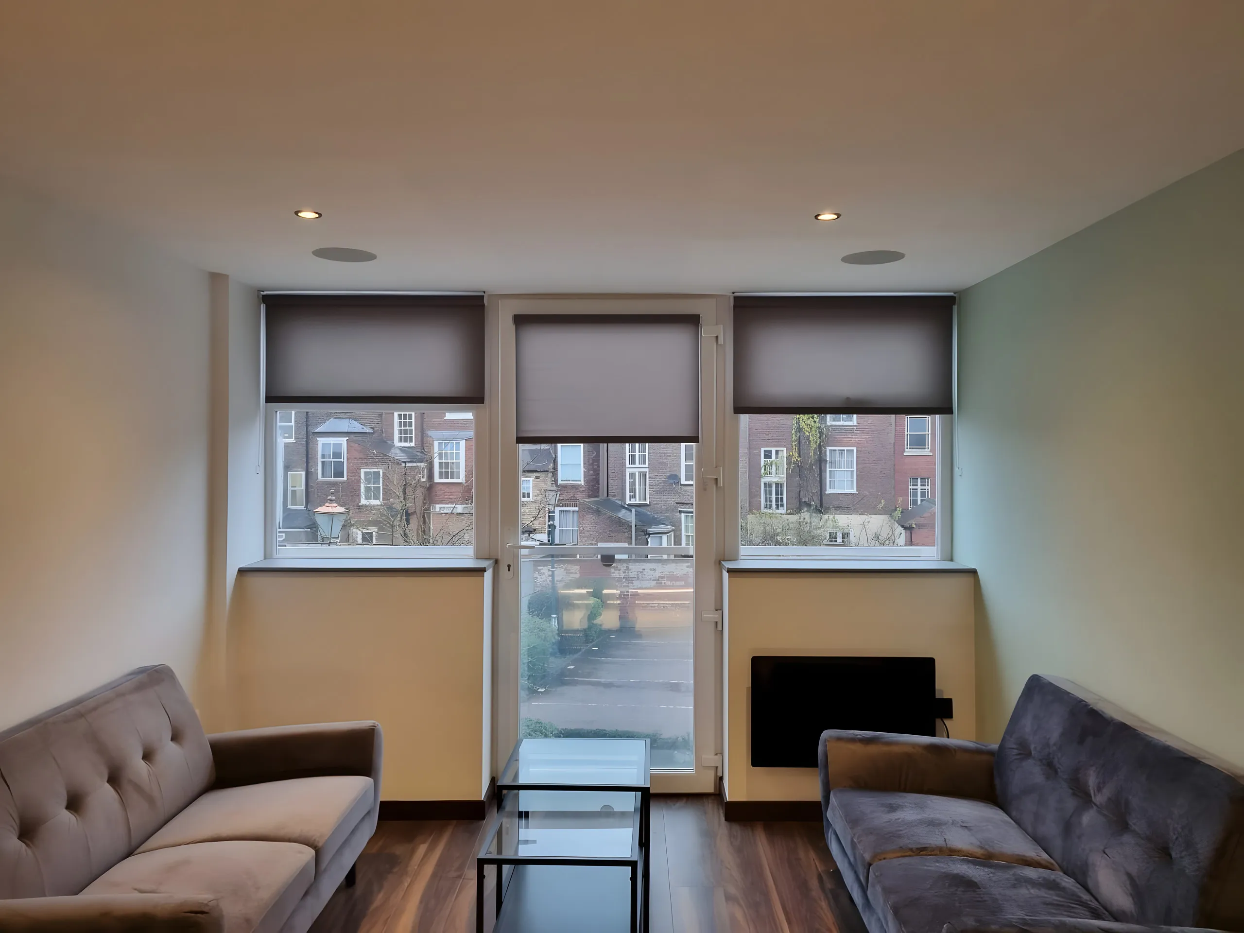 Grey roller blinds on the two windows either side of a chimney breast in a living room