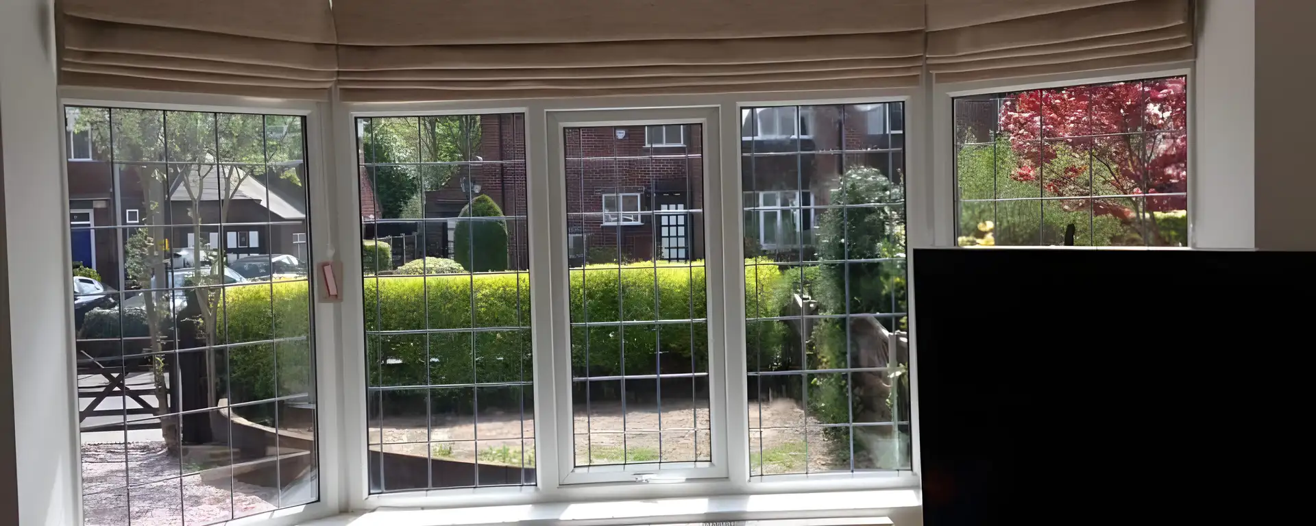 Neutral Roman blinds fitted to each pane of a leaded bay window above a radiator