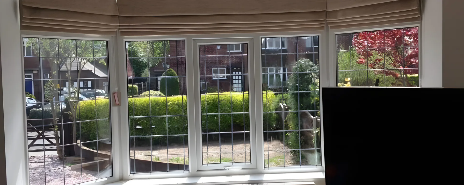 Neutral Roman blinds fitted to each pane of a leaded bay window above a radiator