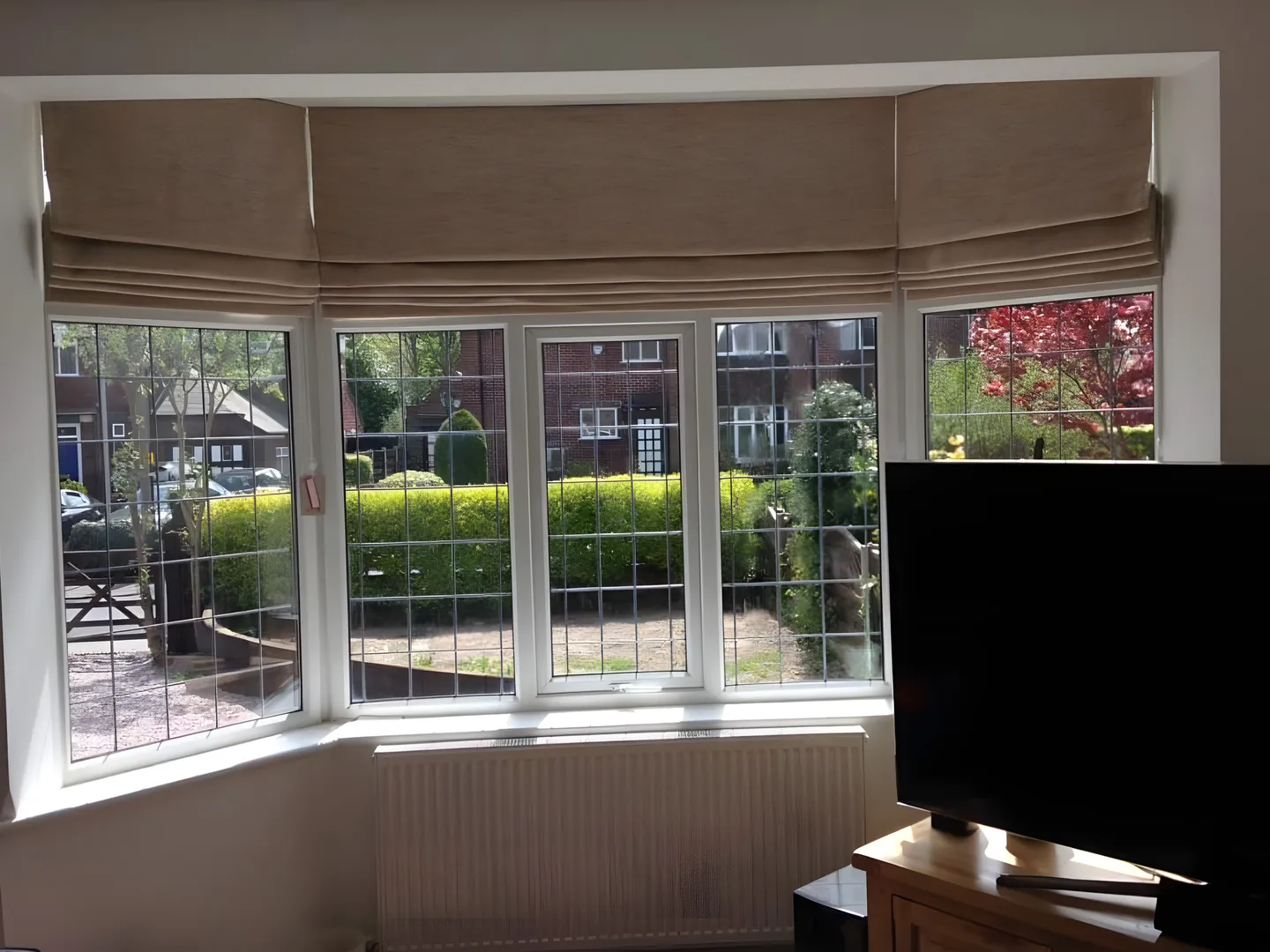 Neutral Roman blinds fitted to each pane of a leaded bay window above a radiator