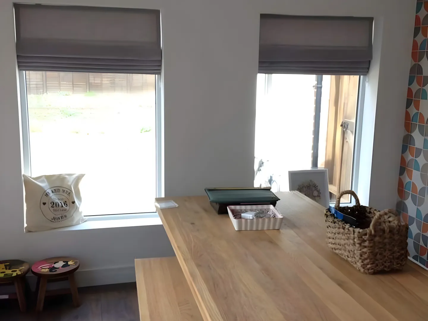 Pair of grey Roman blinds at the windows of a kitchen diner with an oak table